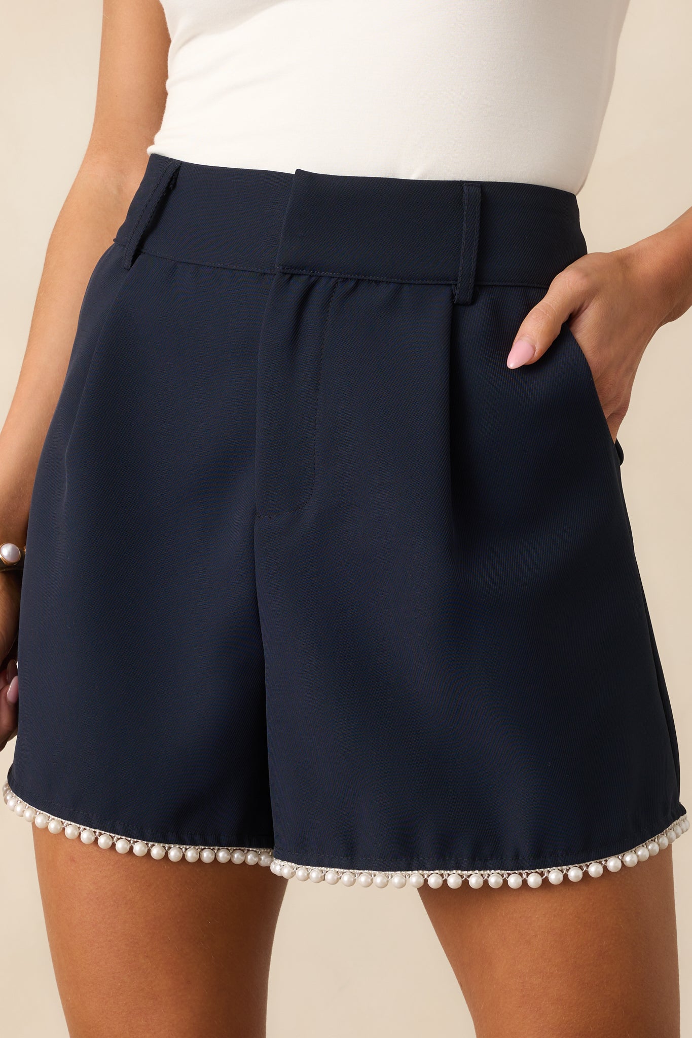 A close-up of the faux pearl trim at the hem, highlighting the delicate beadwork against the navy fabric.