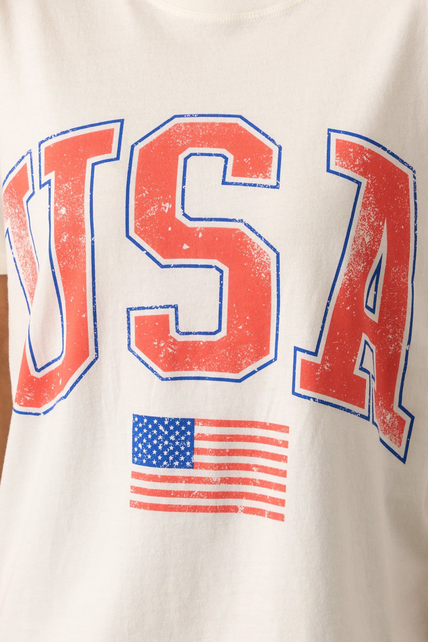 Close-up of the ivory tee’s chest area, focusing on the soft cotton weave and vintage-style 'USA' graphic design.