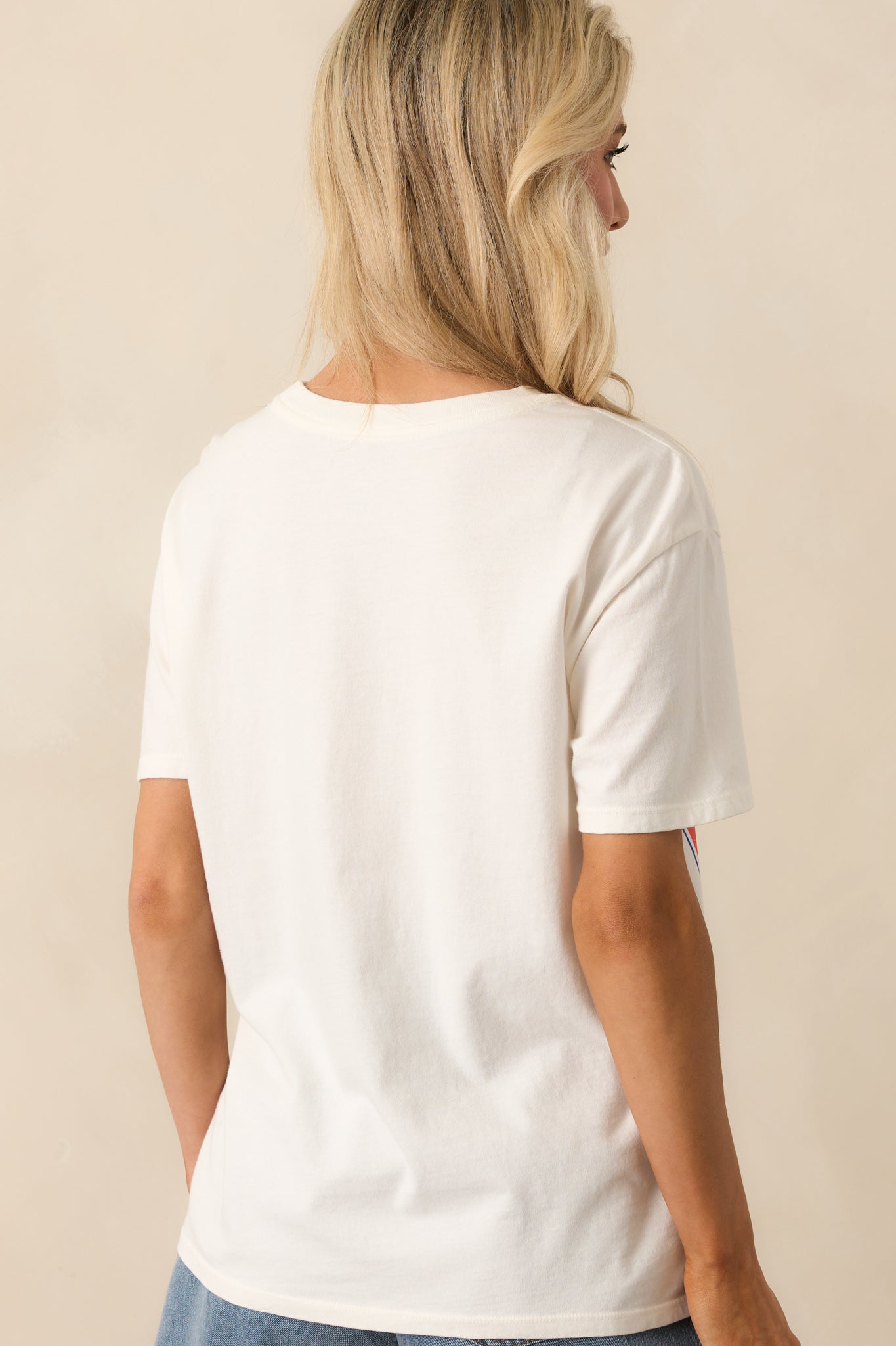 View from behind showing the solid ivory back of the tee and the relaxed cut of the short sleeves.