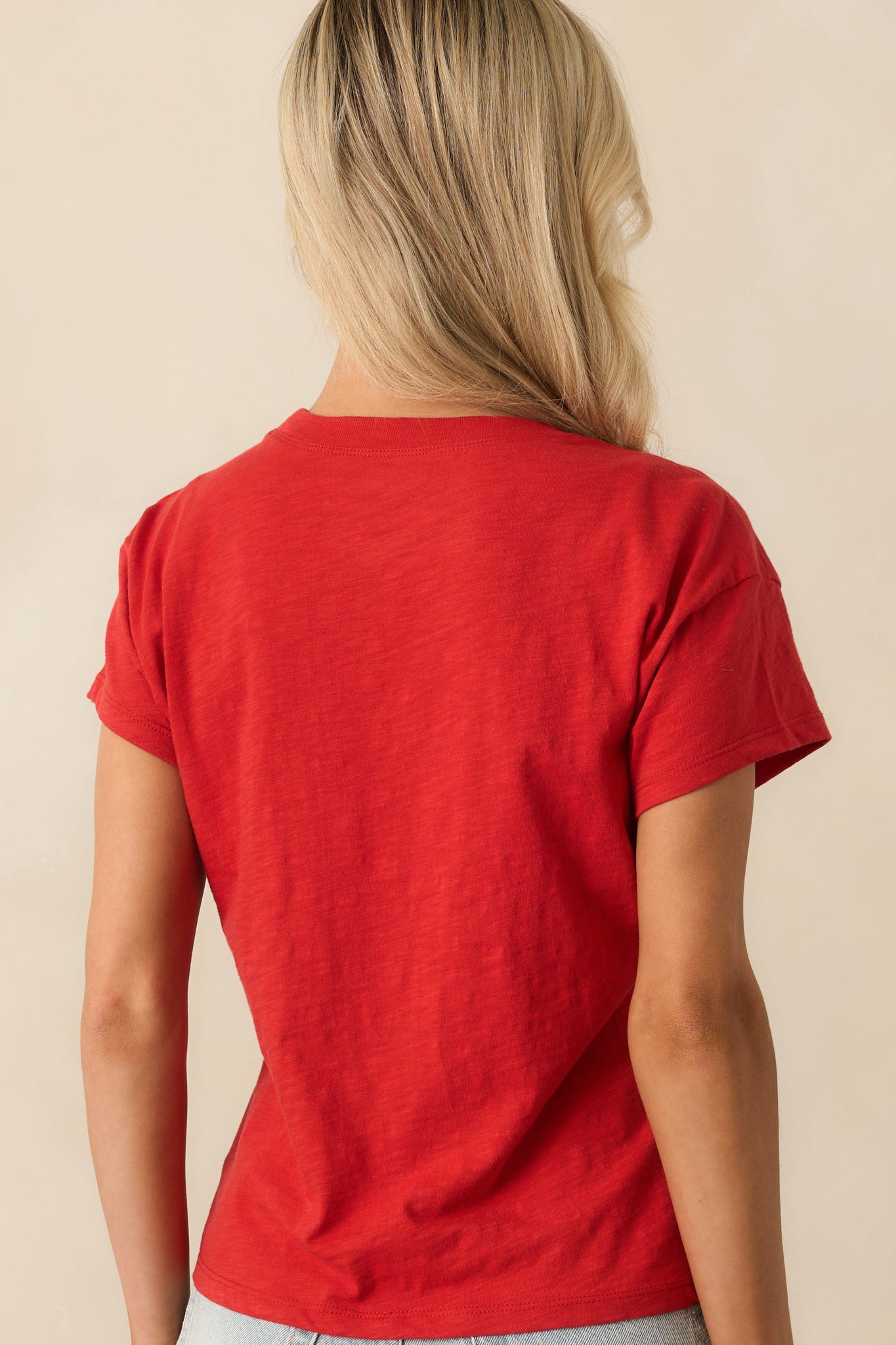 A view from behind of the red tee, showing the smooth jersey material and clean sleeve seams.