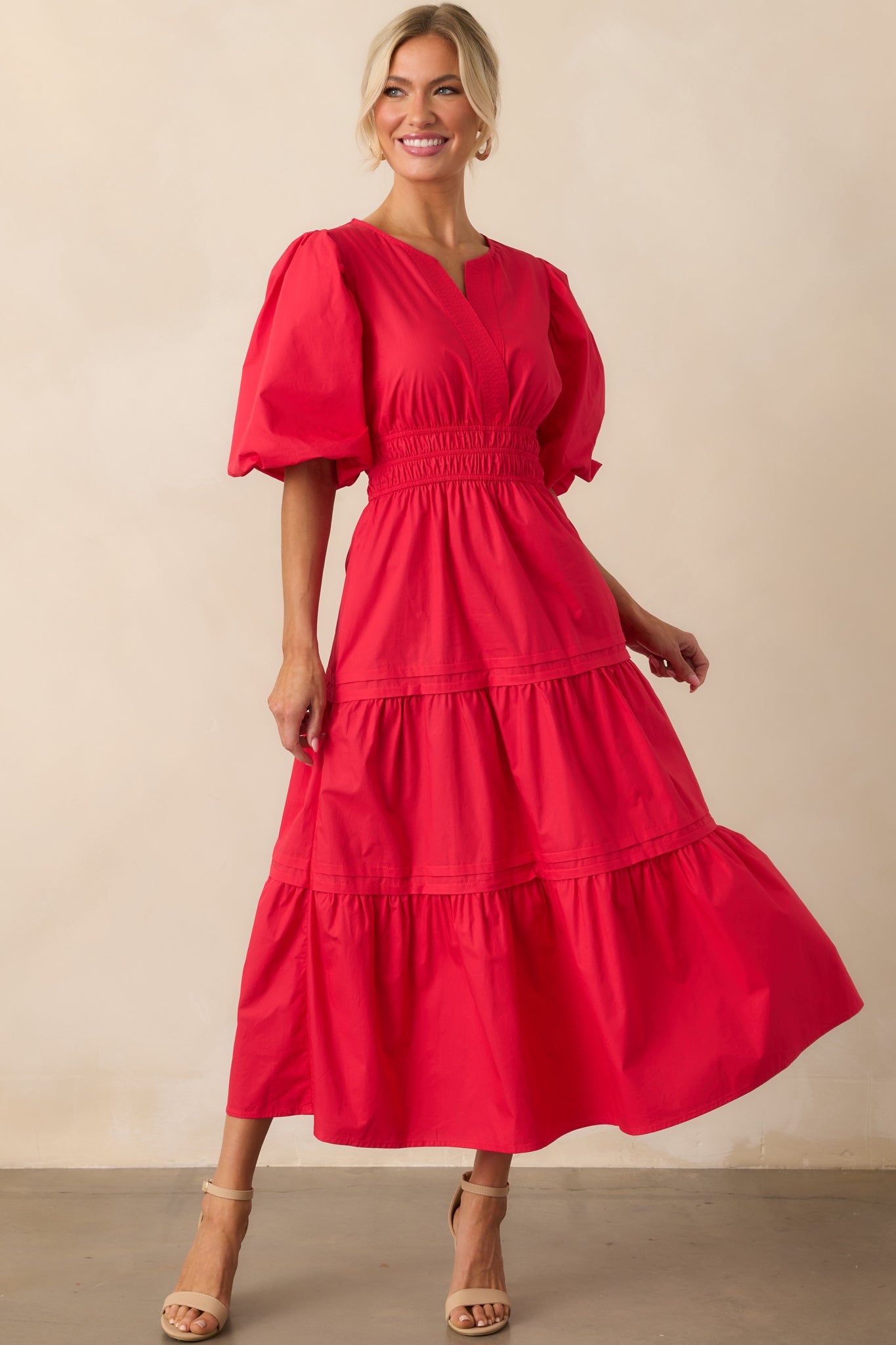 A full-length view of the red maxi dress featuring a notch v-neckline, puff sleeves, and smocked waist.