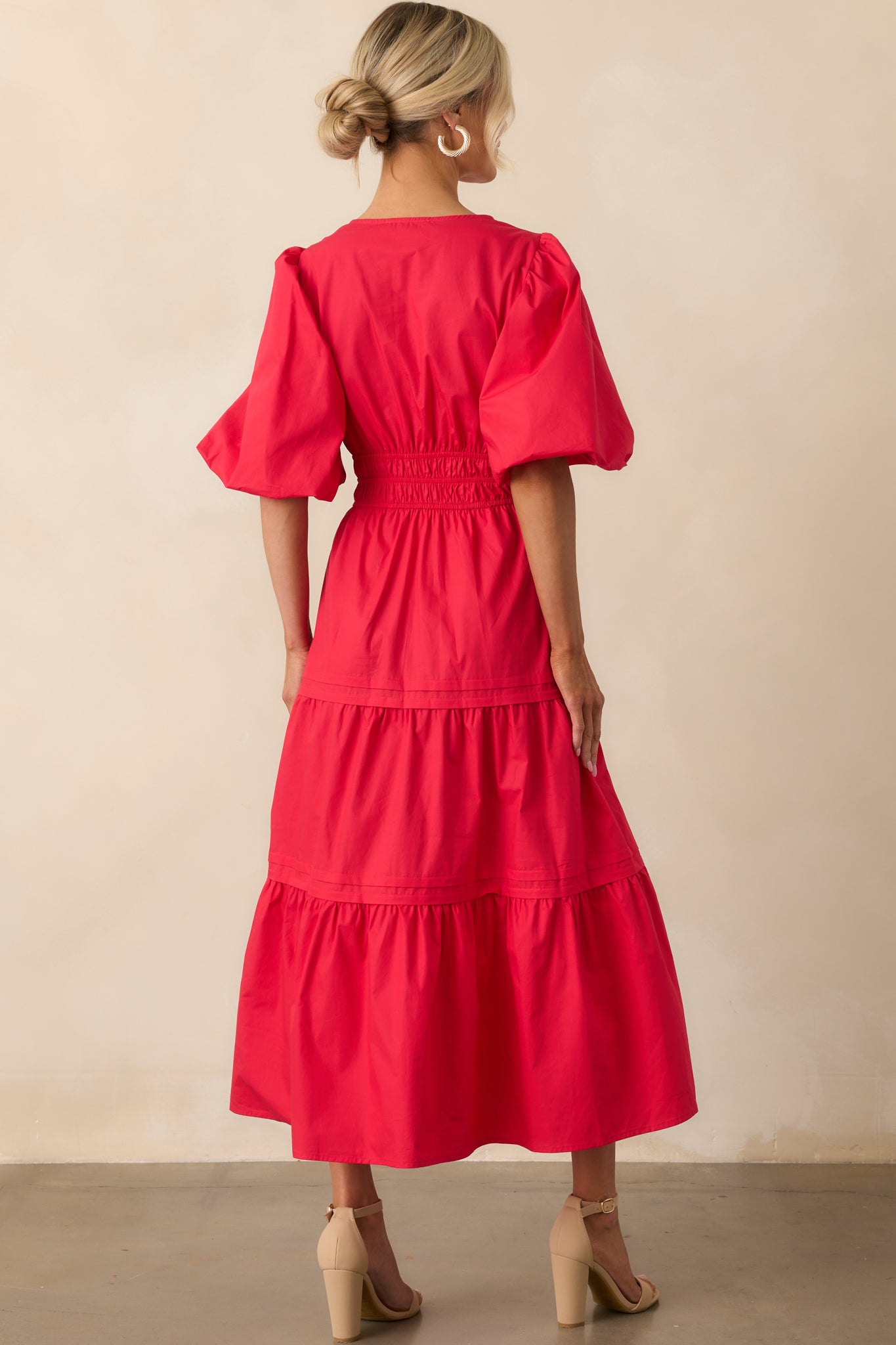 A back view of the red dress displaying the gathered waistline and gentle flow of the tiered maxi skirt.