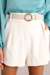 Close up view of these shorts that feature a high waisted design, hook and bar closure, zipper, belt loops, and functional pockets in the front.