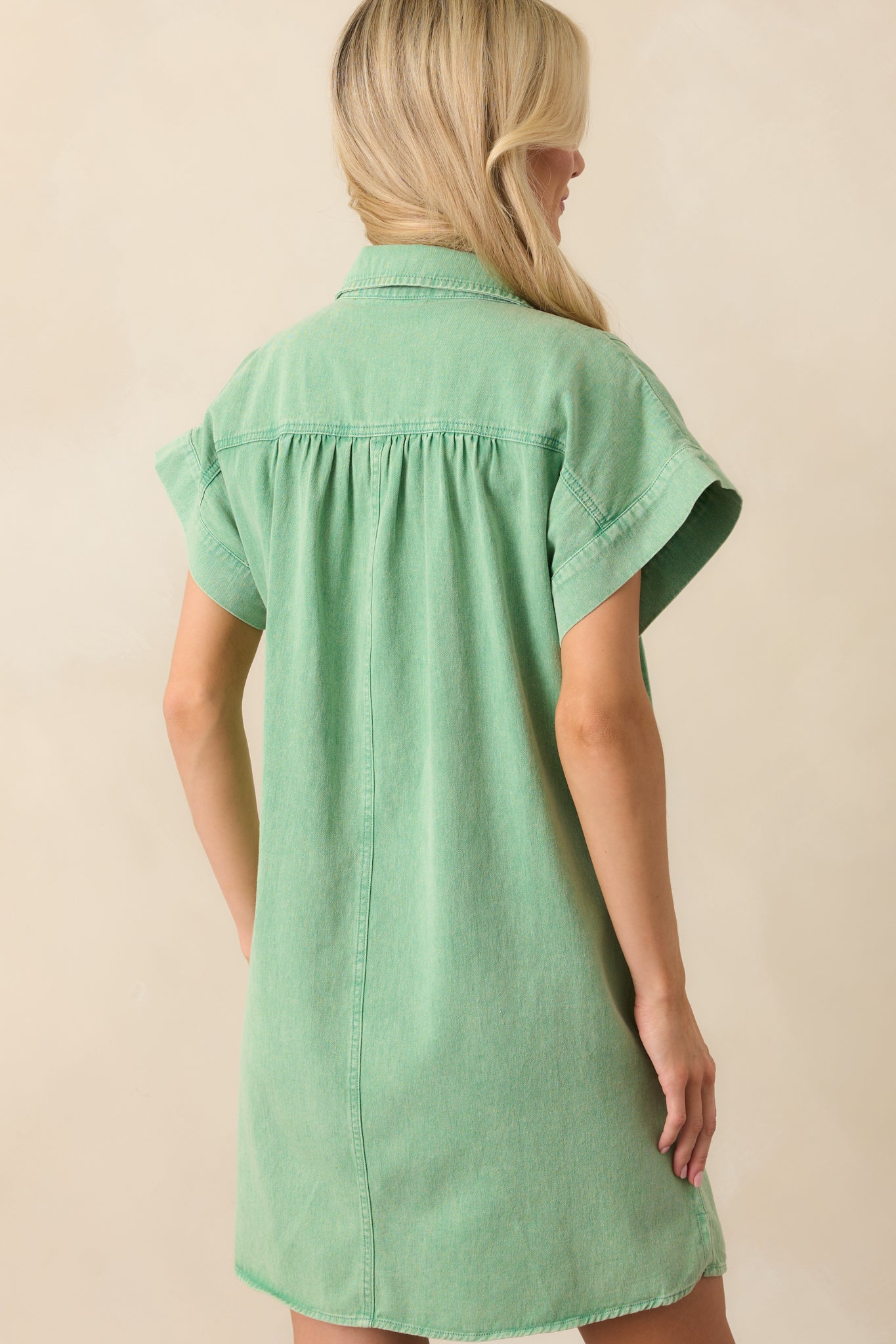 Back view of the mini dress, highlighting the simple, clean design with a slight flare and the versatility of the light wash denim fabric.