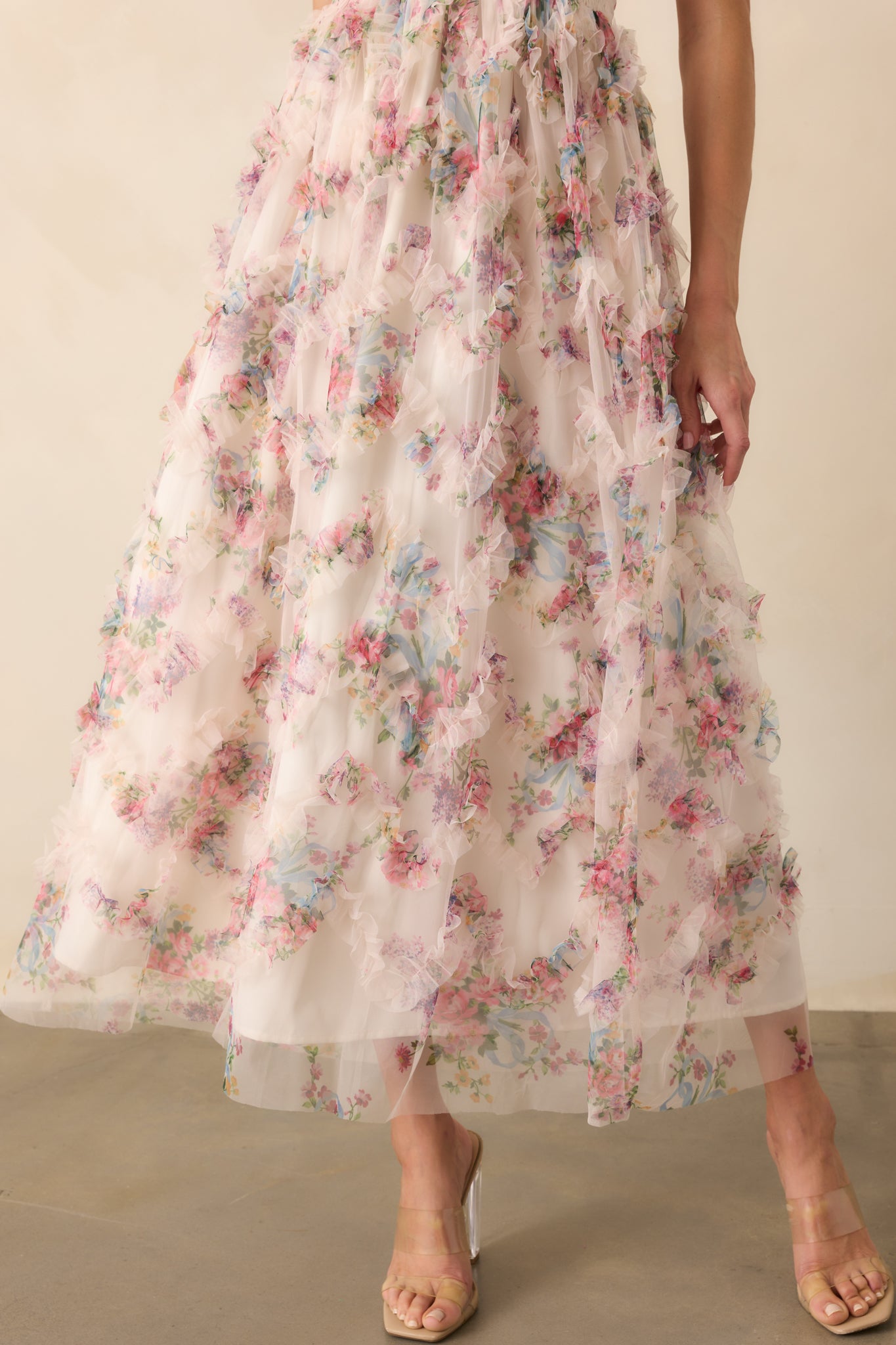 Close-up of the skirt showcasing the sheer pink multicolor floral print overlay with delicate tulle ruffles layered over the ivory lining, highlighting the soft texture and flow of the fabric.
