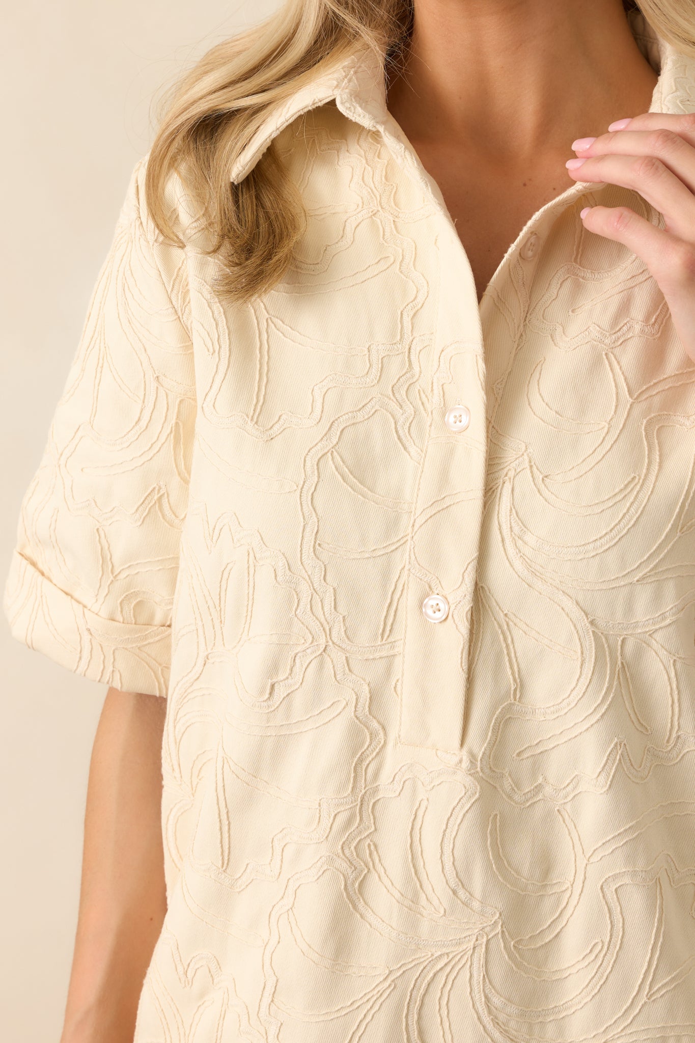 Tight detail of the floral embroidery on the denim fabric, revealing the tonal stitching and textured cotton weave.