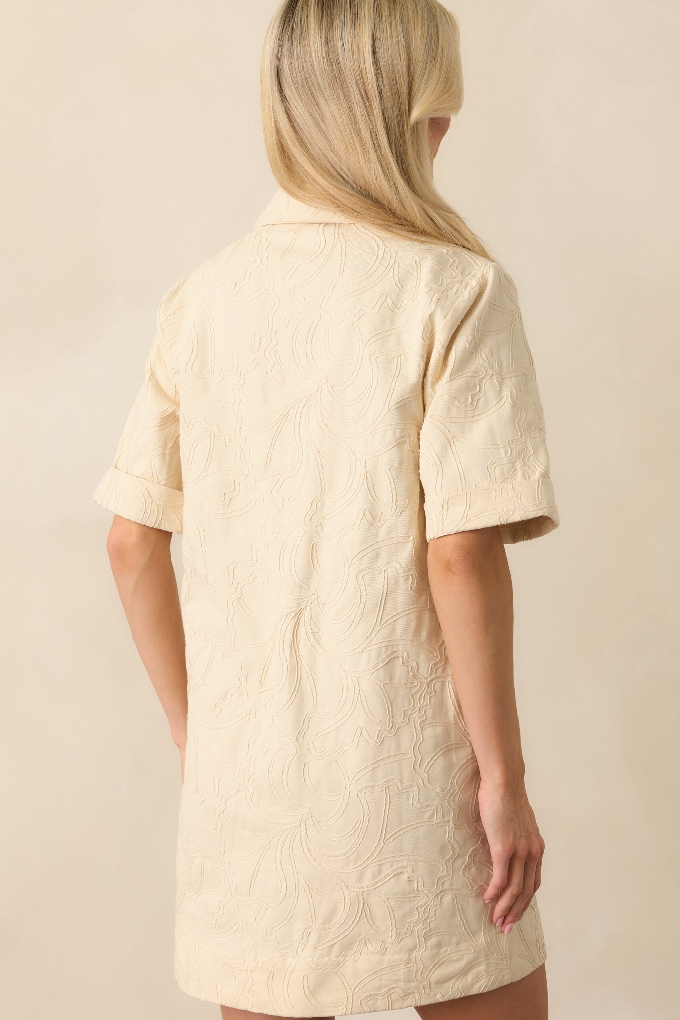 Rear view of the dress highlighting the back yoke seam, continuation of the monochrome embroidery, and the smooth finish of the denim fabric.