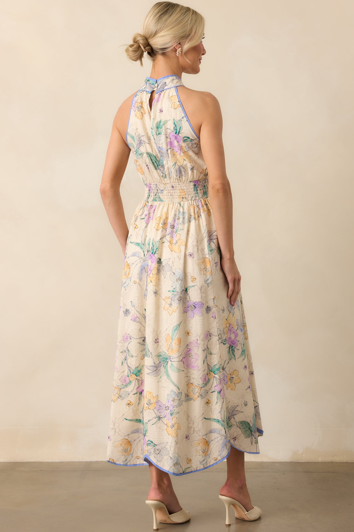 Full back view of the dress highlighting the halter neck strap with button closure, exposed upper back, blue trim accents, and the structured flow of the panel skirt from behind.