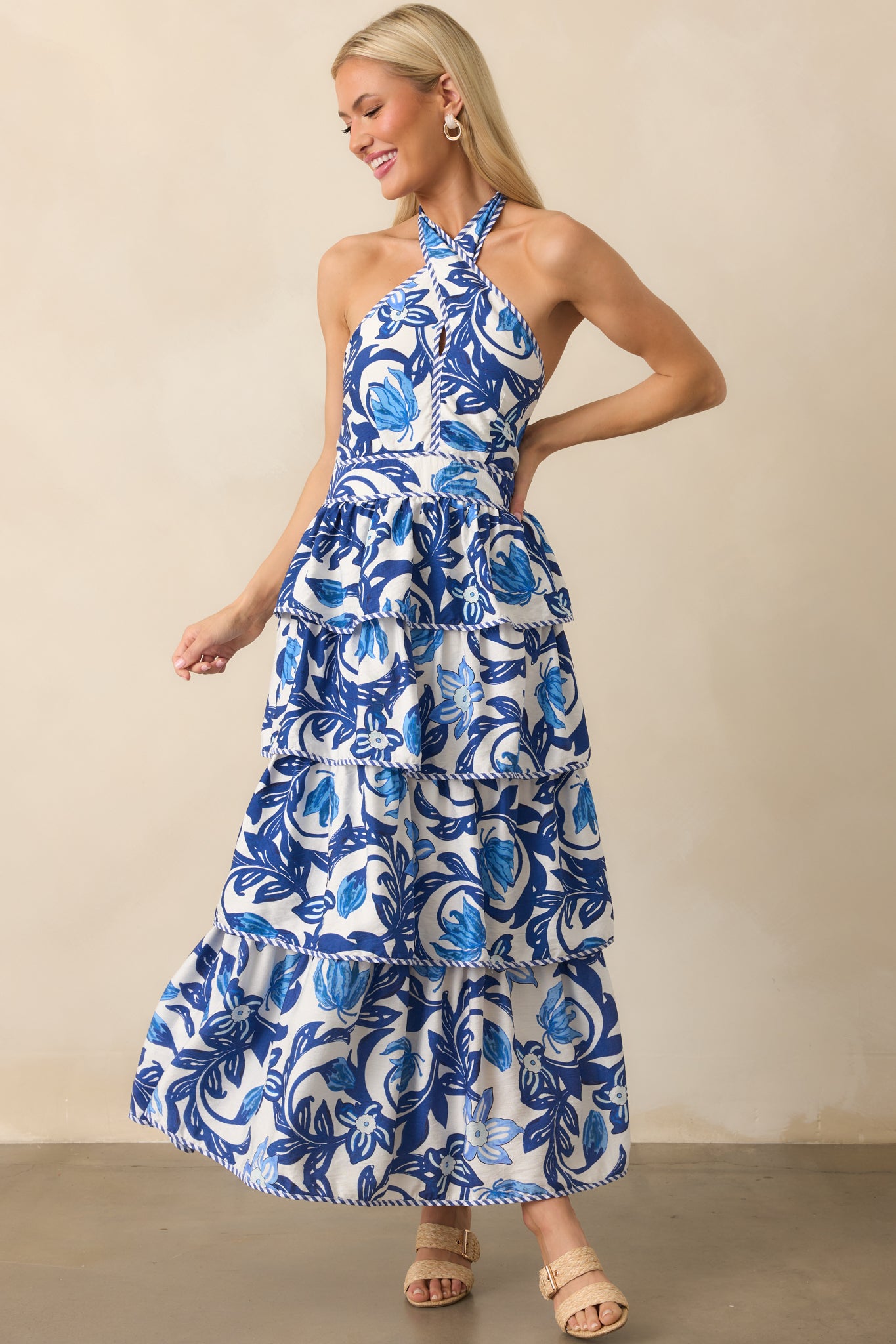 Front view of the blue floral maxi dress featuring an adjustable self-tie halter v-neckline and a flowing tiered skirt.