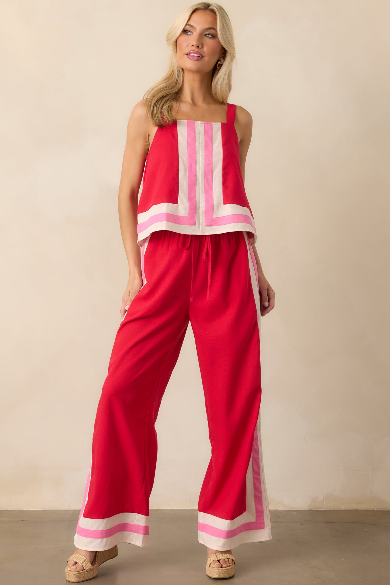 Front view of the red pants featuring ivory and pink contrast trim, wide leg silhouette, and a high-rise elastic waistband.
