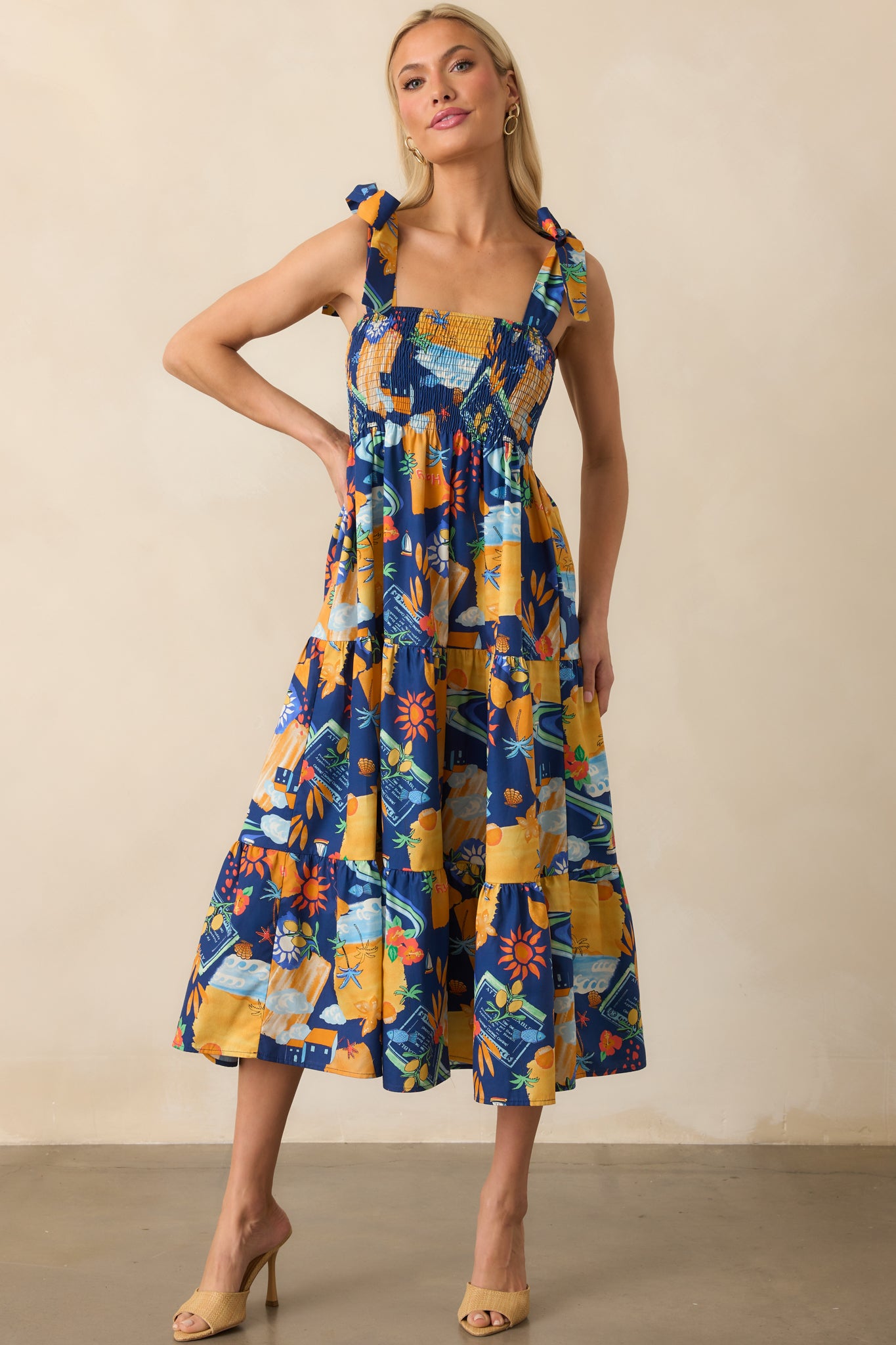 Front view of the navy midi dress showcasing the orange multicolor tropical print, square neckline, and tiered skirt.
