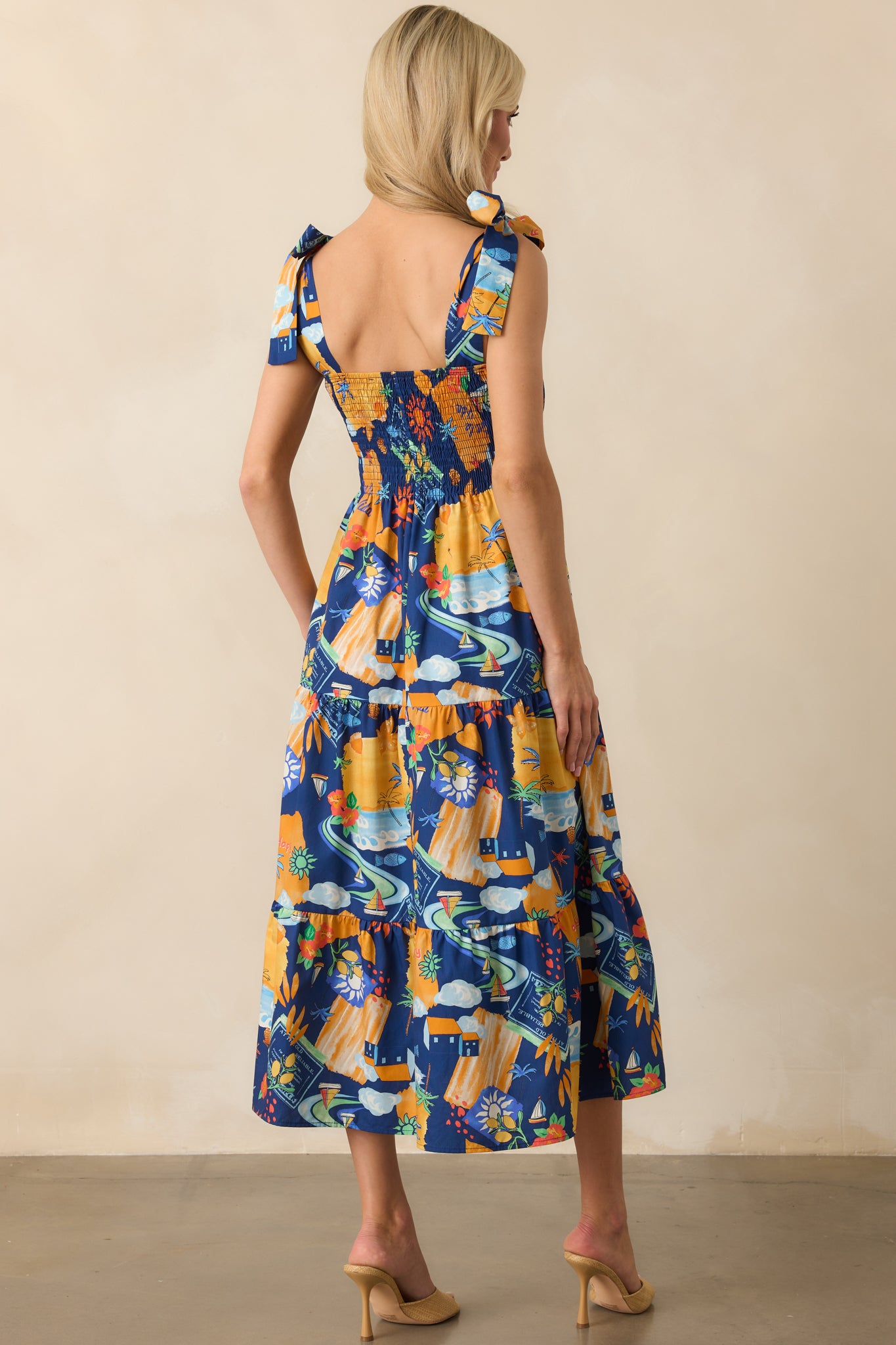 Rear view of the dress highlighting the fully smocked back and the tied shoulder straps, with the tropical print continuing throughout.