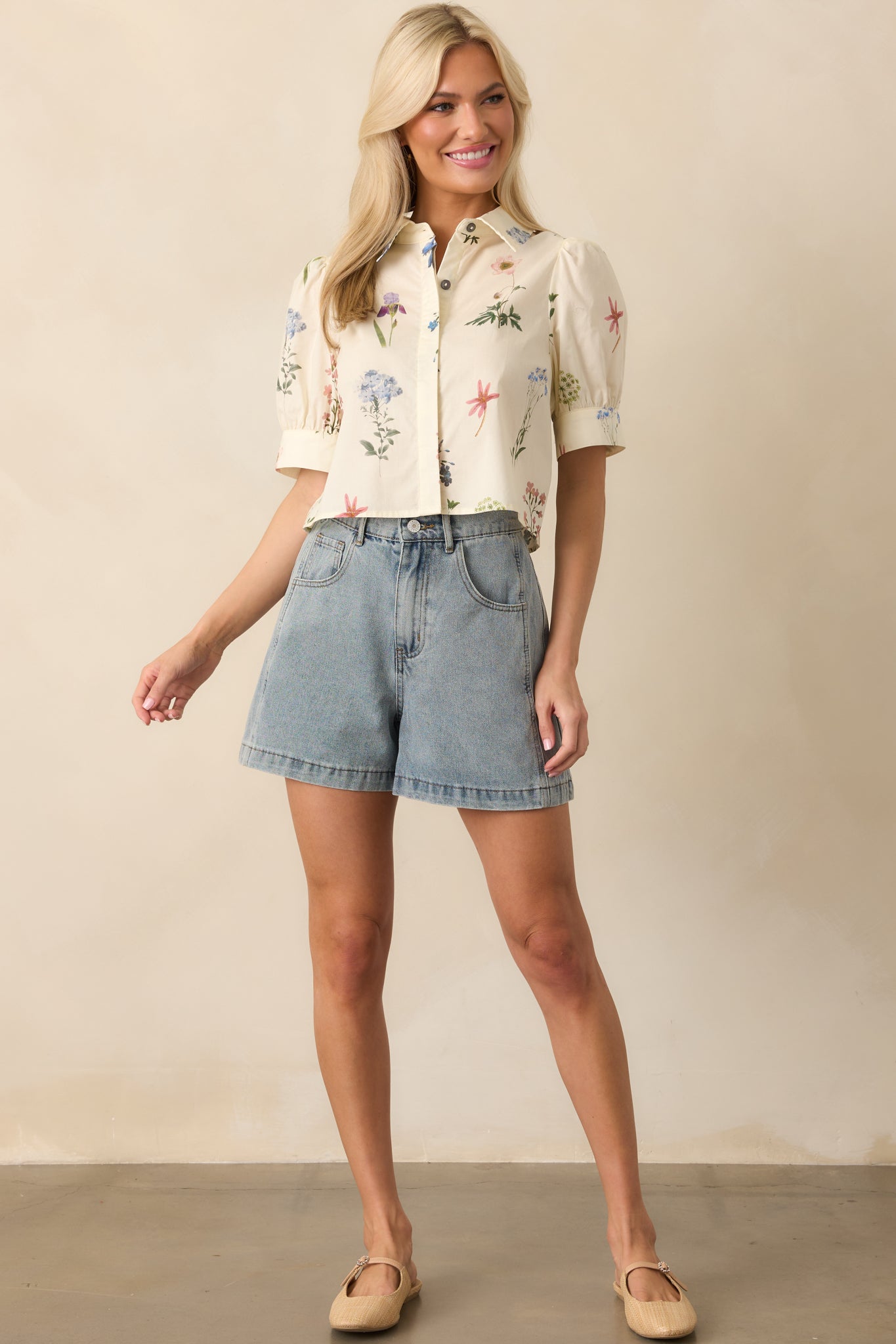 Front-facing full body image showing the ivory floral top with short puff sleeves and a functional button front design.