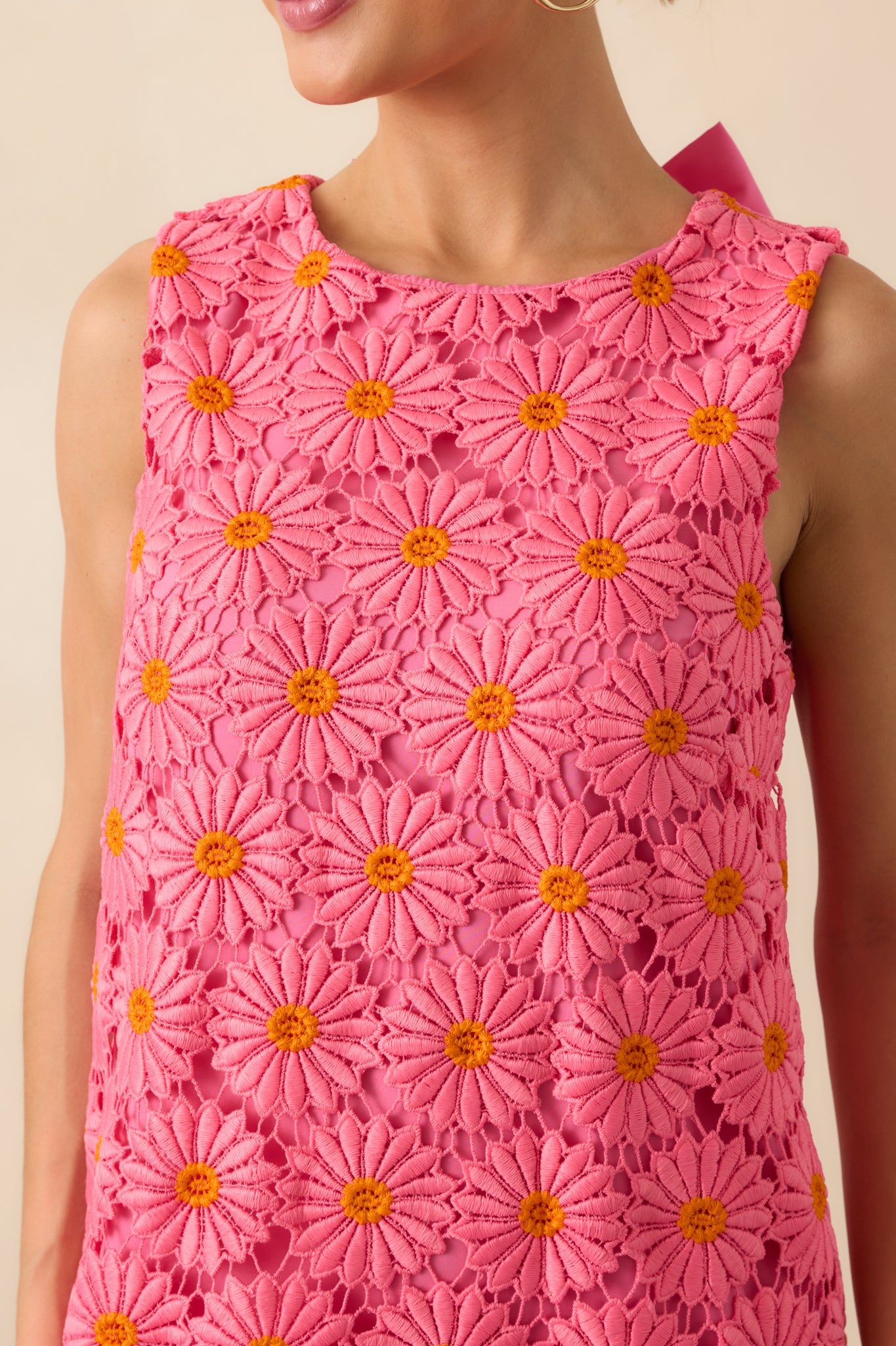 A close-up view of the mini dress’s front showing the hot pink and orange floral embroidered lace overlay, round neckline, and delicate scalloped edges.