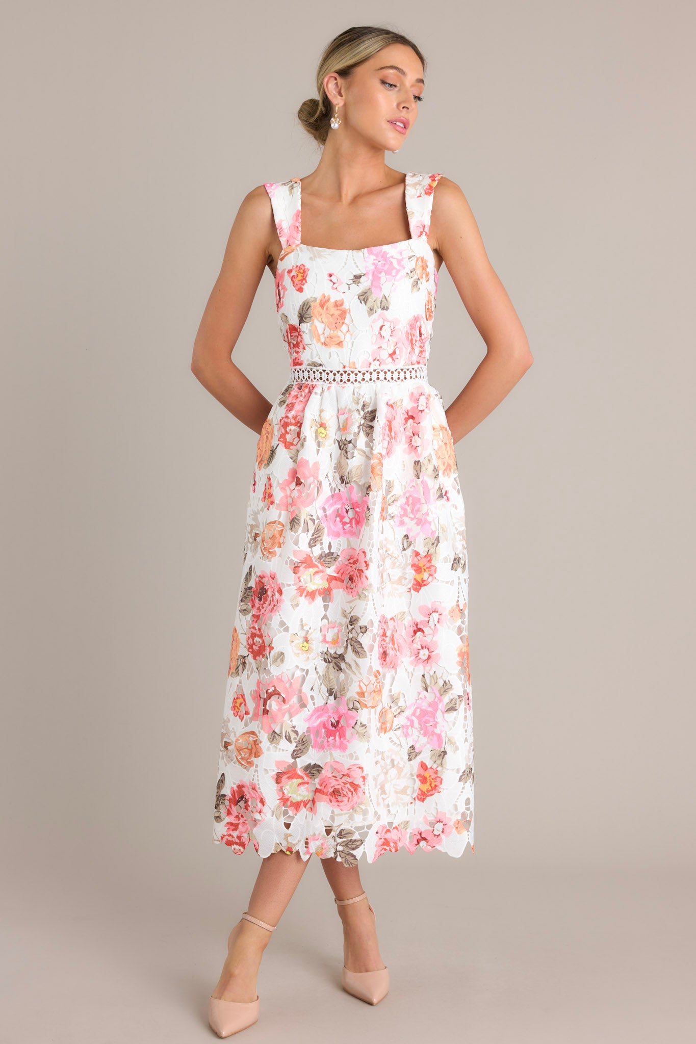 Elegant white multi floral midi dress featuring a square neckline, fitted bodice, crocheted waist detail, and functional pockets, completed by a lace mid-length skirt.