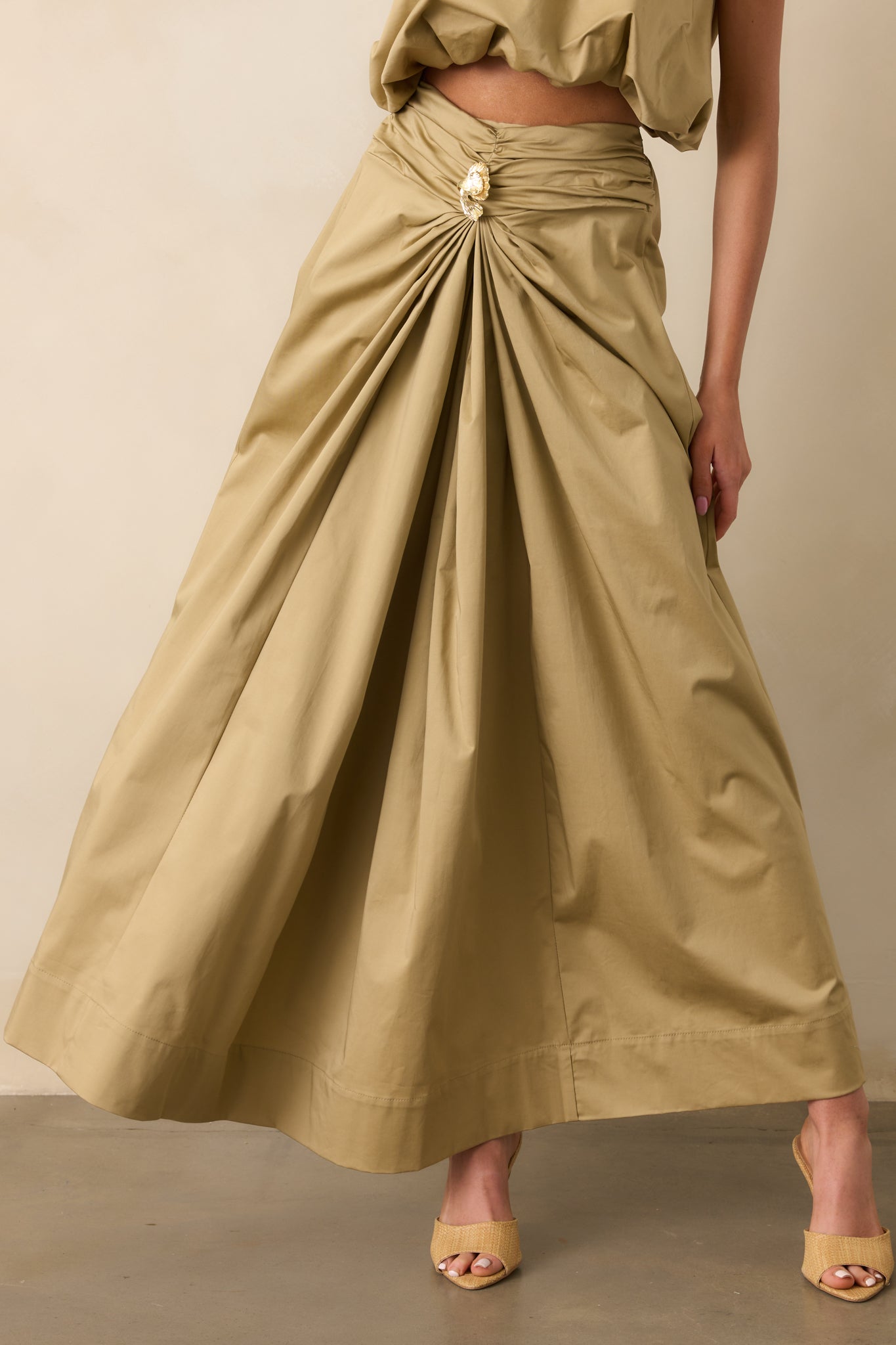 Cropped view of the ruched waistband and front draping, showcasing the gathered texture and tan fabric.