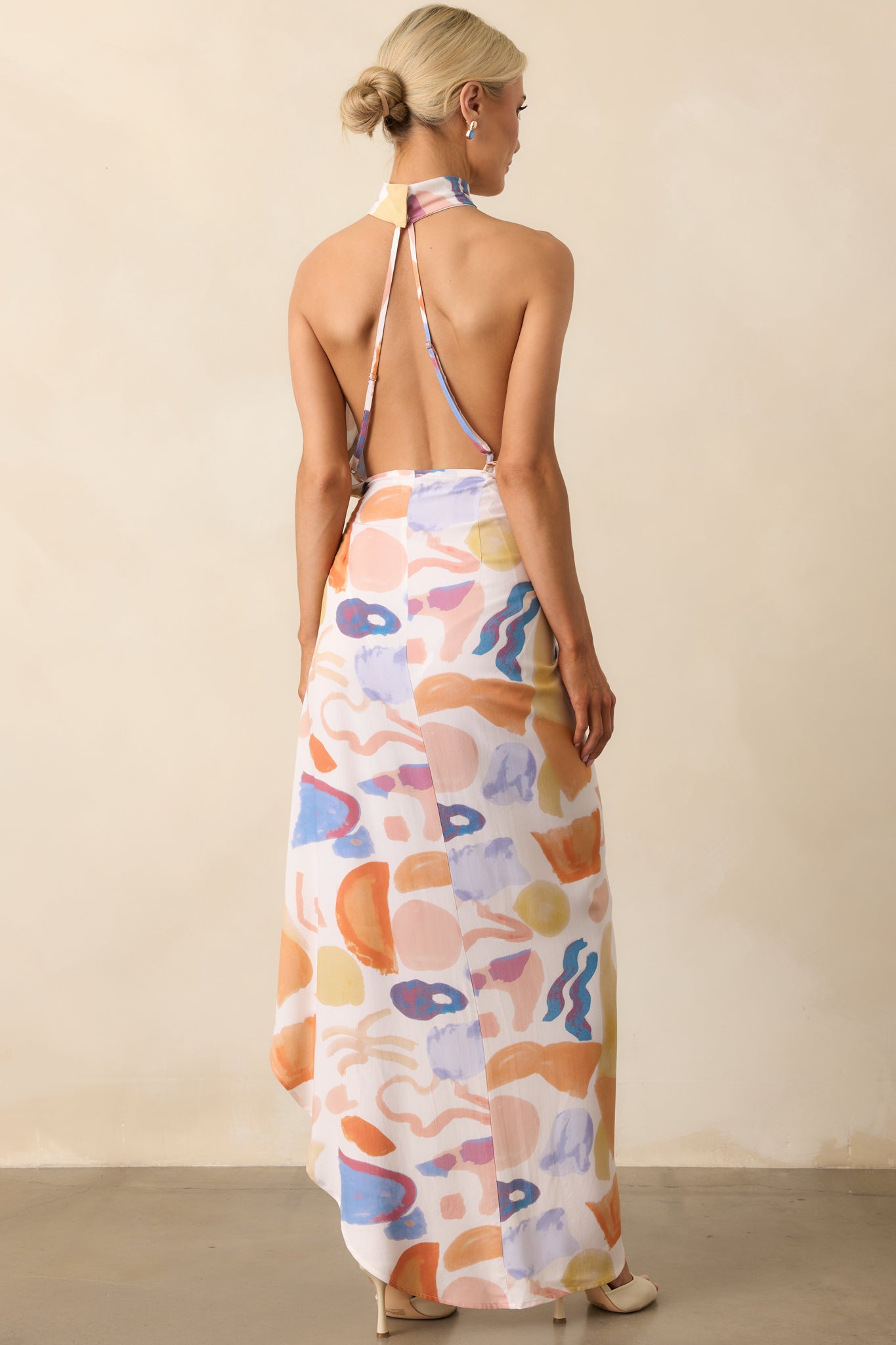 Rear view of the dress displaying the open back with adjustable crisscross straps and the continued abstract print across the skirt.