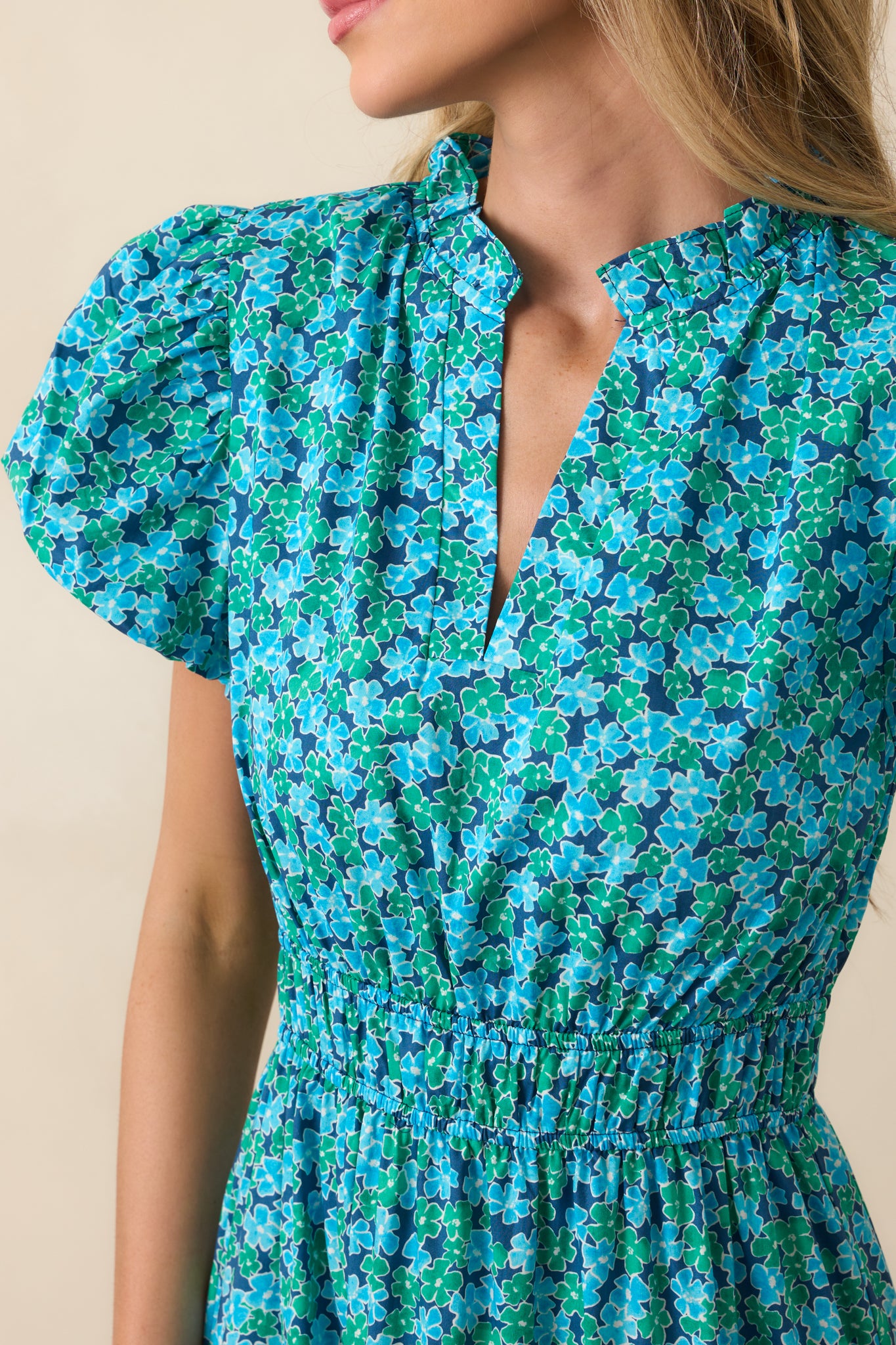 Close-up of the neckline and sleeve, showing the ruffle trim, floral pattern, and gathered elastic details.