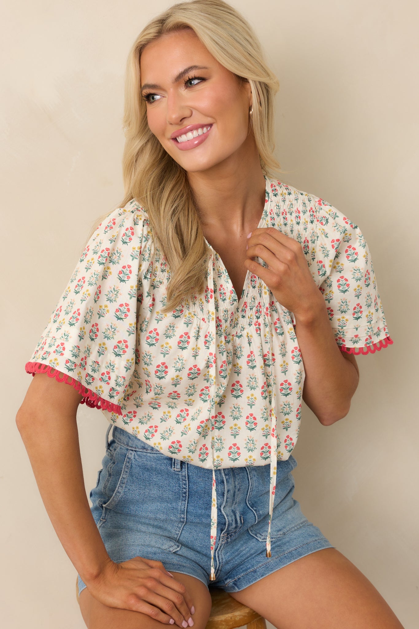 An angled front view of the top emphasizing the gathered smocked neckline and floral pattern throughout.