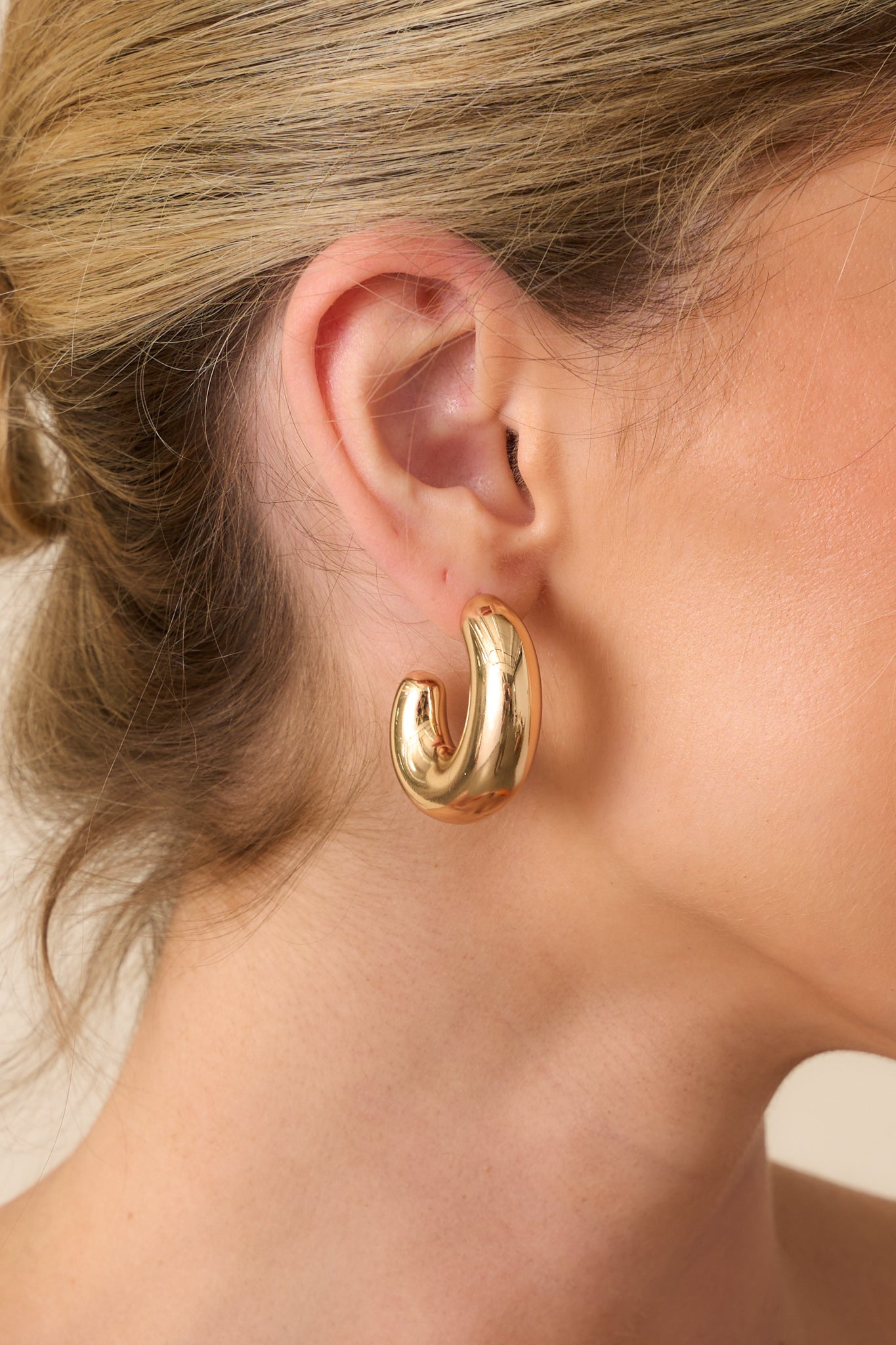 Tight detail capturing the smooth, high-shine gold finish and the subtle curvature of the dome-shaped open hoops.