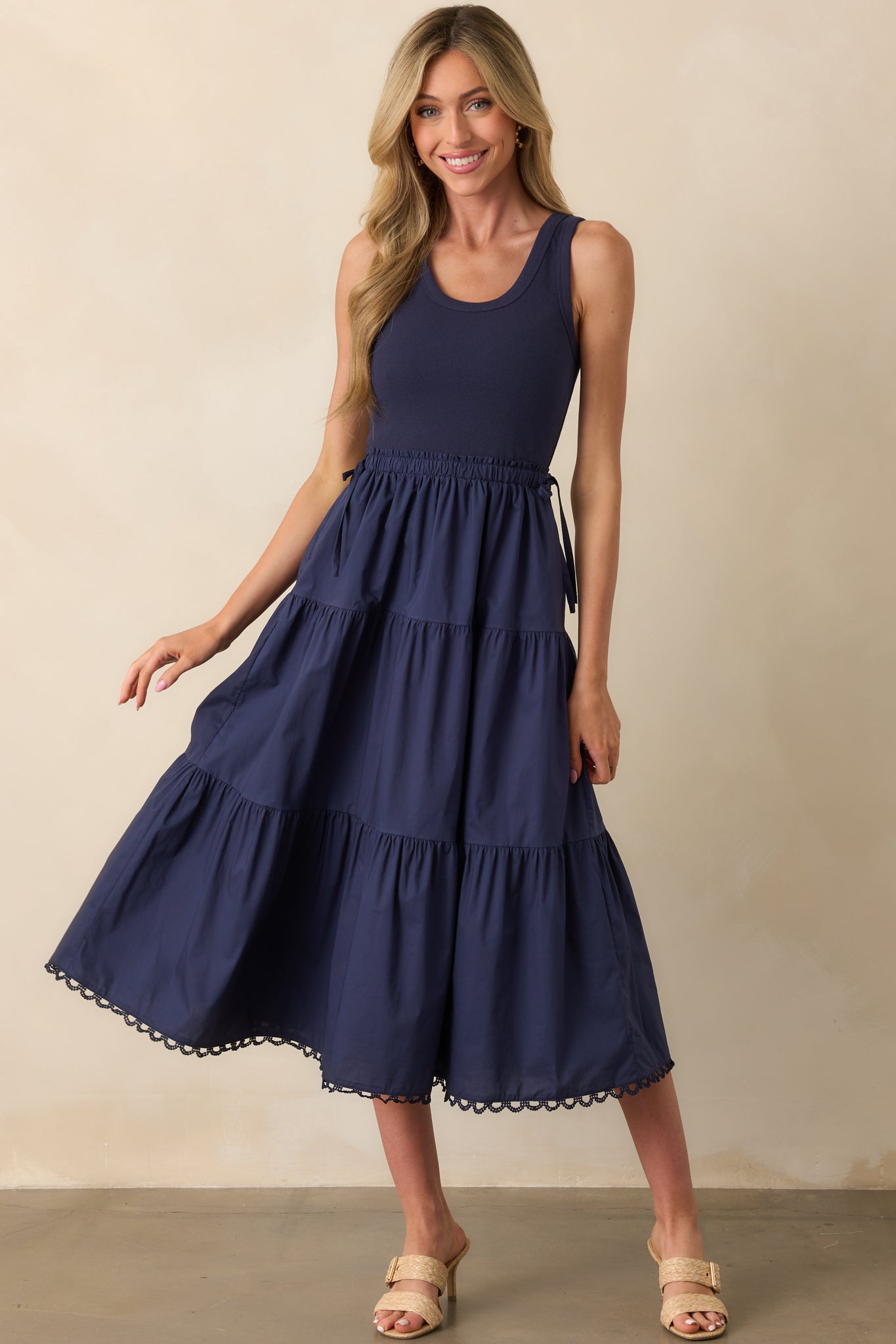 Front view of a navy midi dress with a scoop neckline, ribbed bodice, and tiered skirt.