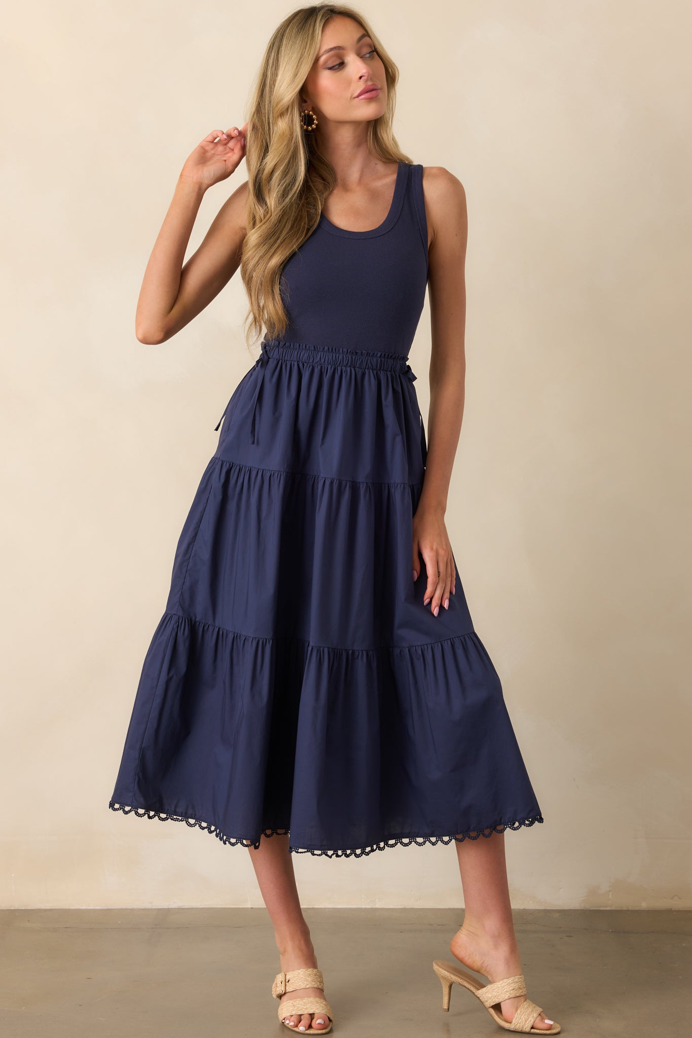 Three-quarter front angle of the navy midi dress, emphasizing the textured tiering and waist detail.