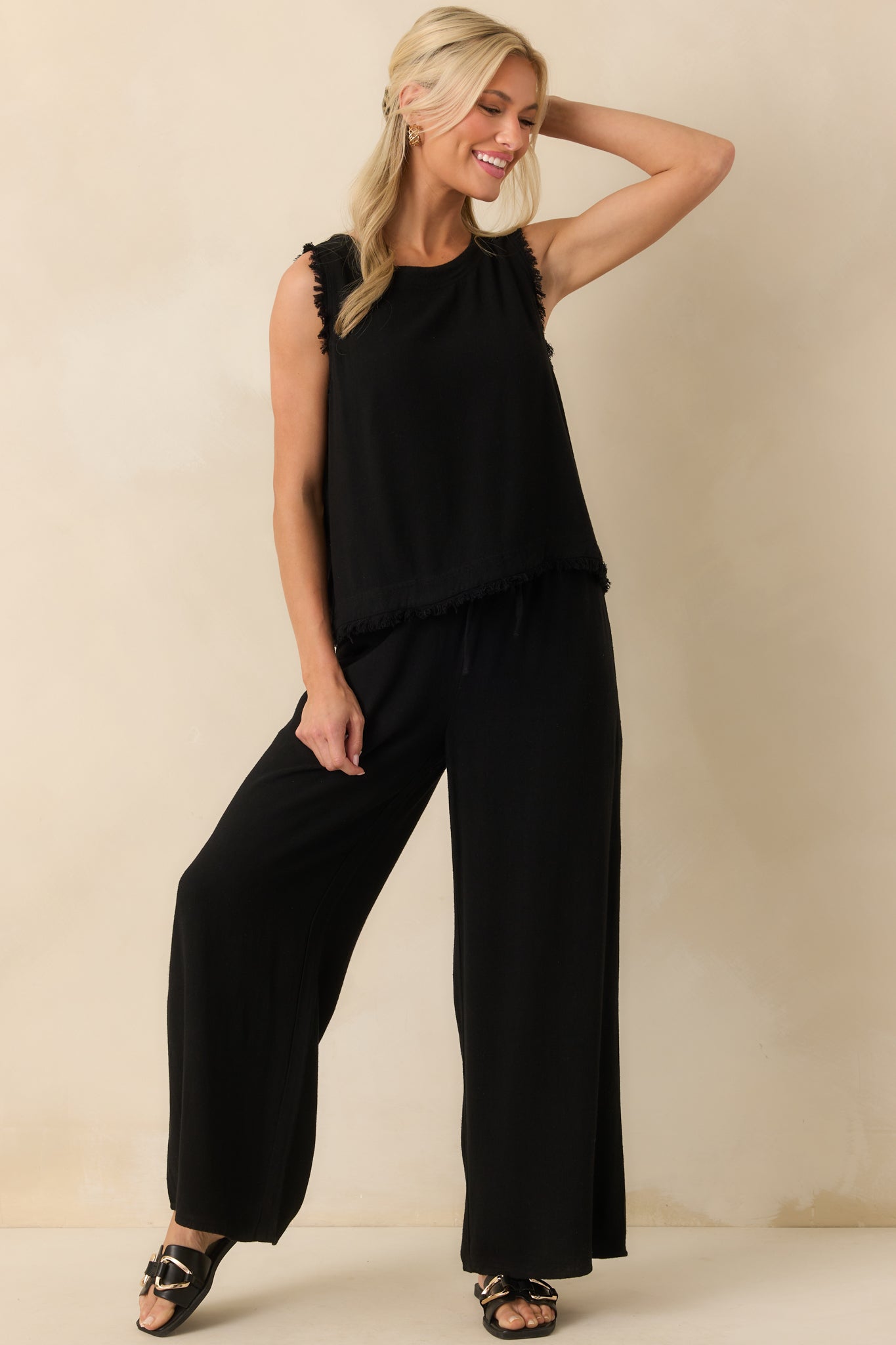 Front view of the black tank showing the crew neckline and relaxed fit with frayed shoulder detailing.
