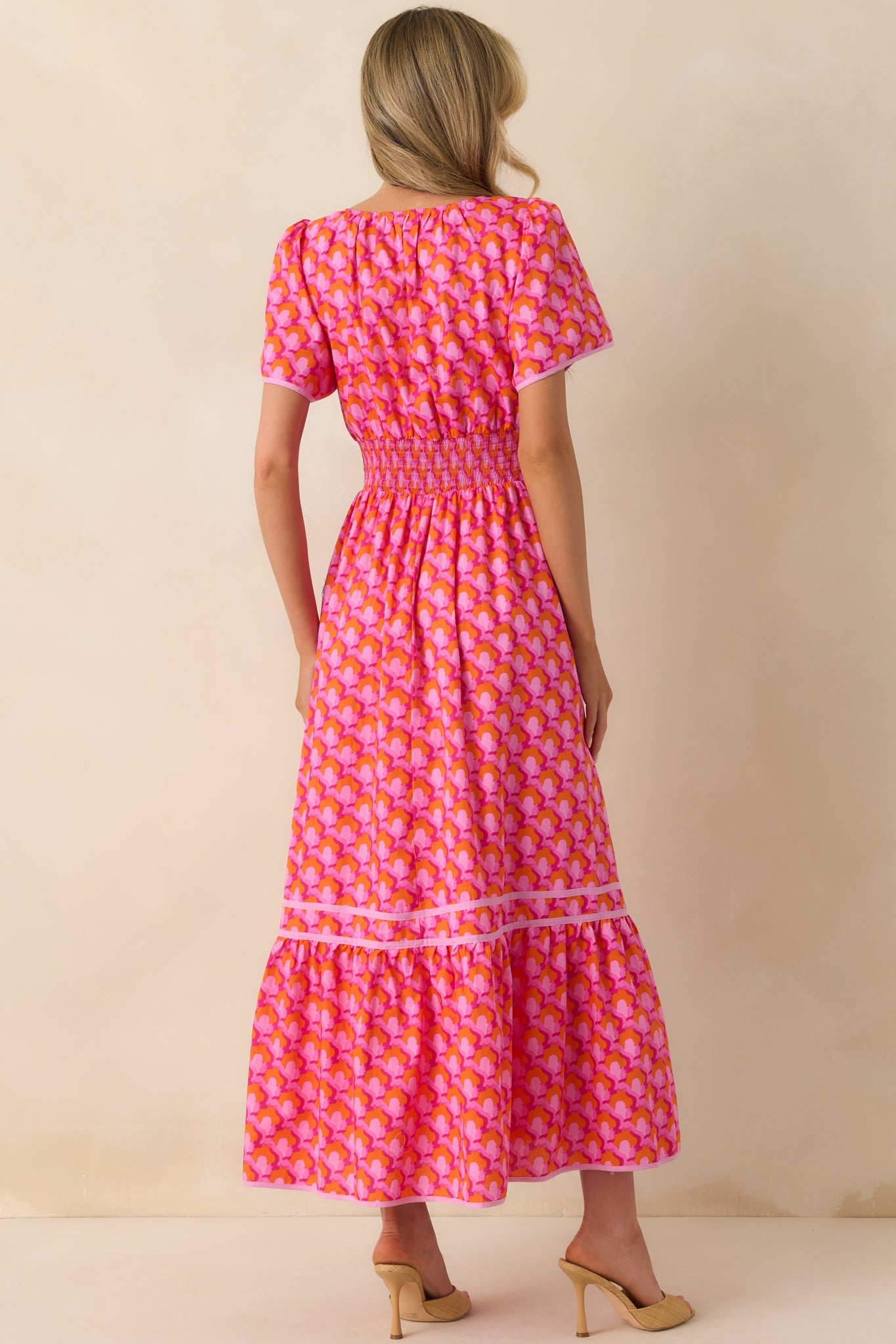 Back view of the dress displaying the continuation of the abstract print, smocked waist from behind, and the tiered skirt design.