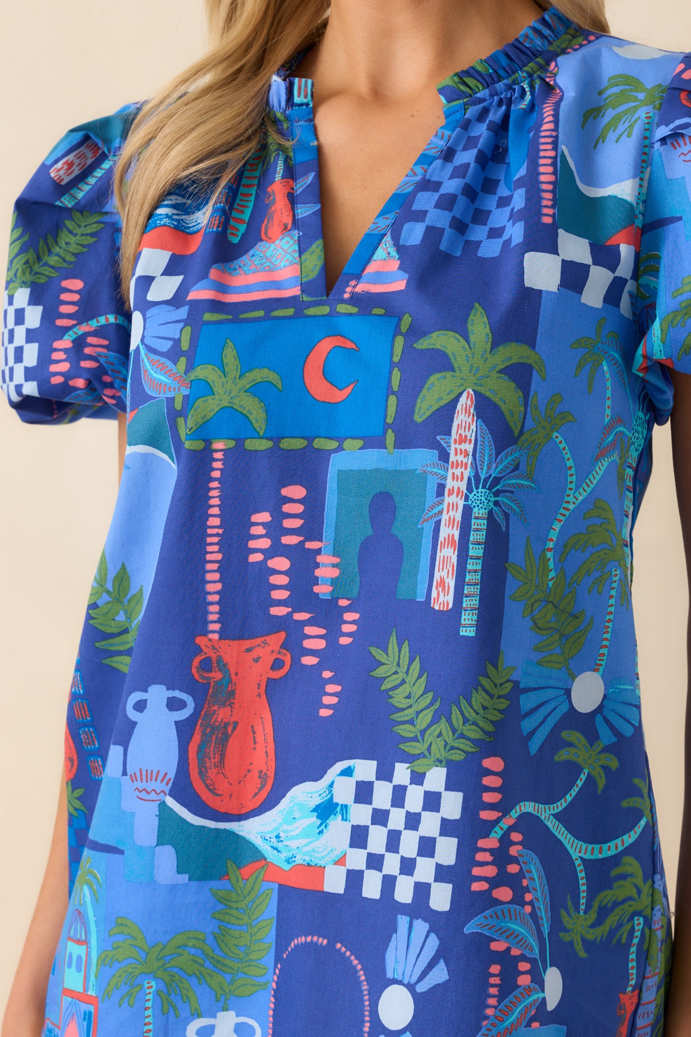 Close-up of the neckline and sleeve showing the ruffle trim, tropical print colors, and soft texture of the fabric.