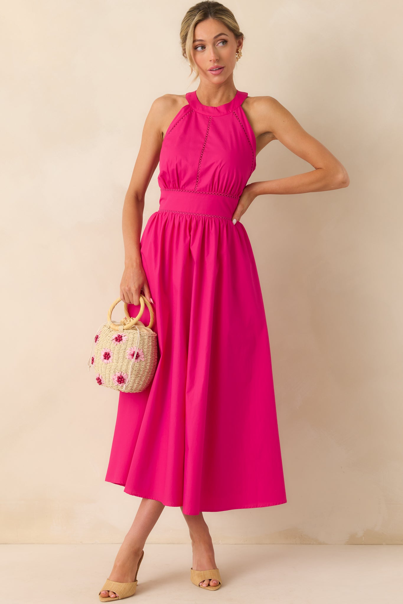 Front view of a fuchsia pink maxi dress with a halter neckline and embroidered trim across the bodice.
