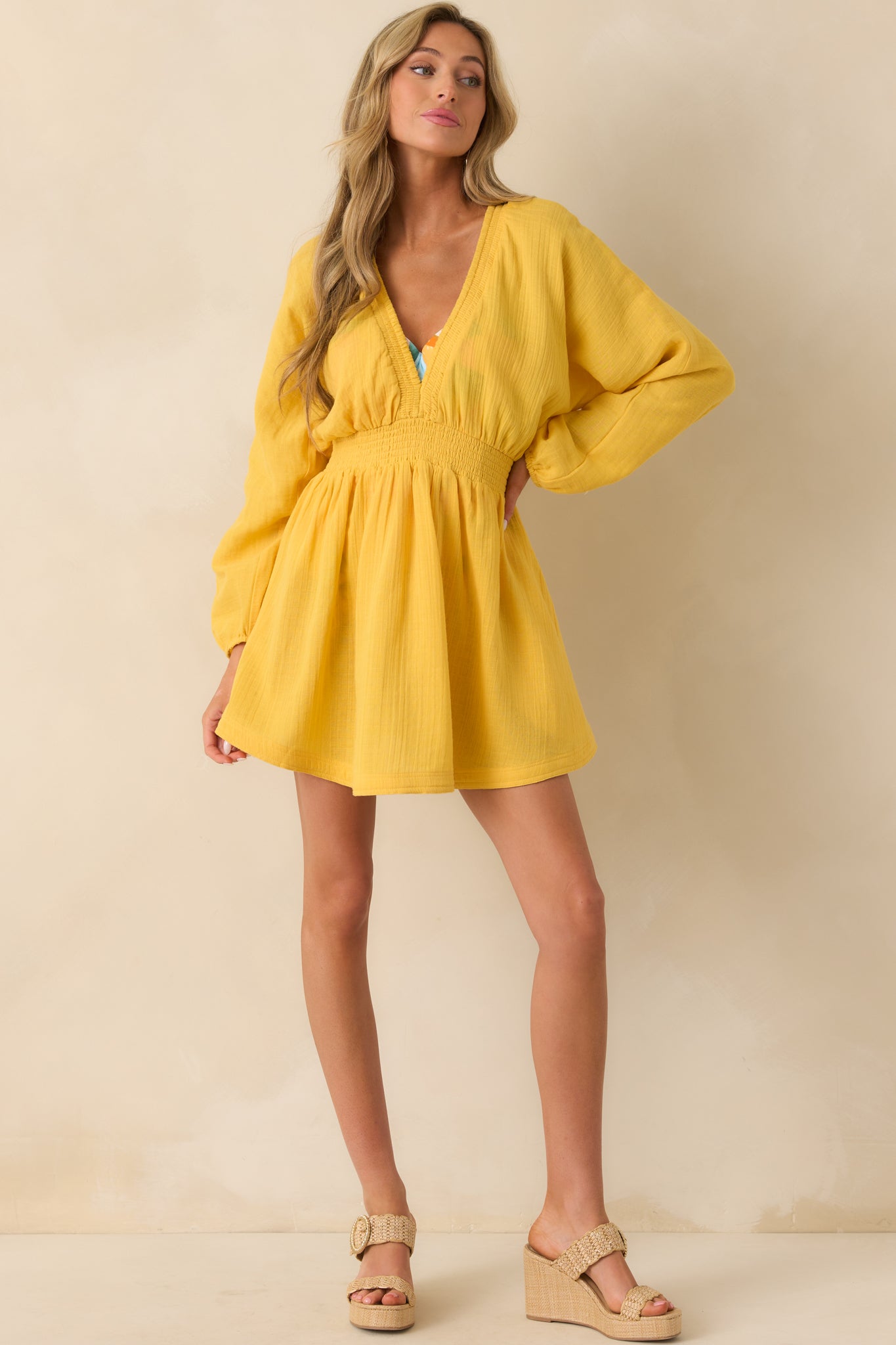 A full-length view of the yellow mini dress featuring a smocked waistband and relaxed silhouette, styled with elastic cuffs.