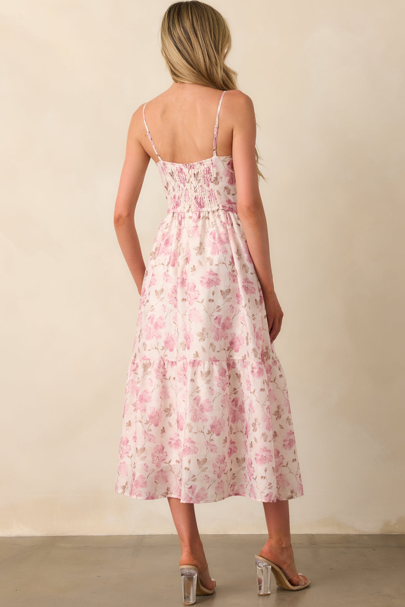 A view from behind of the pink chiffon dress showing the smocked back panel, zipper closure, and thin straps.