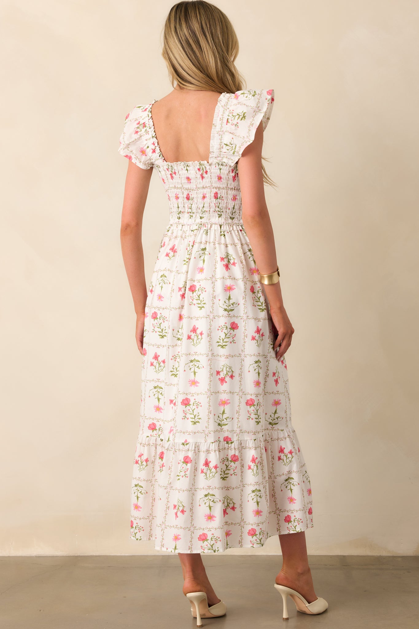 Rear view of the dress displaying the smocked back panel, elastic flutter sleeves, and continuation of the tiered skirt.