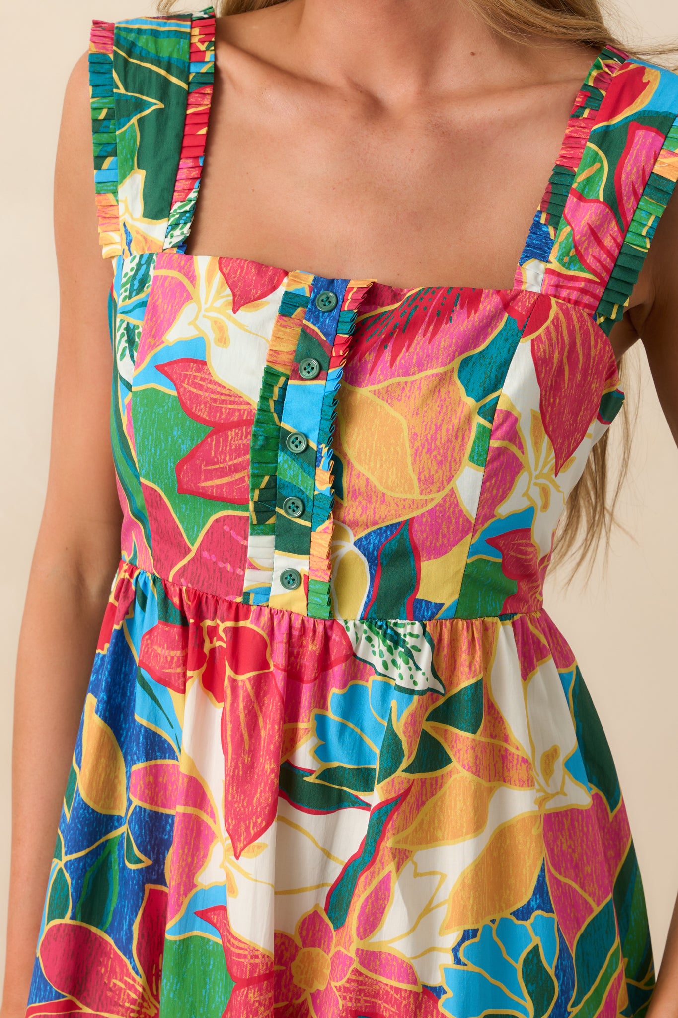 Close-up shot of the bodice showing the faux button accents, square neckline, and tropical floral print.
