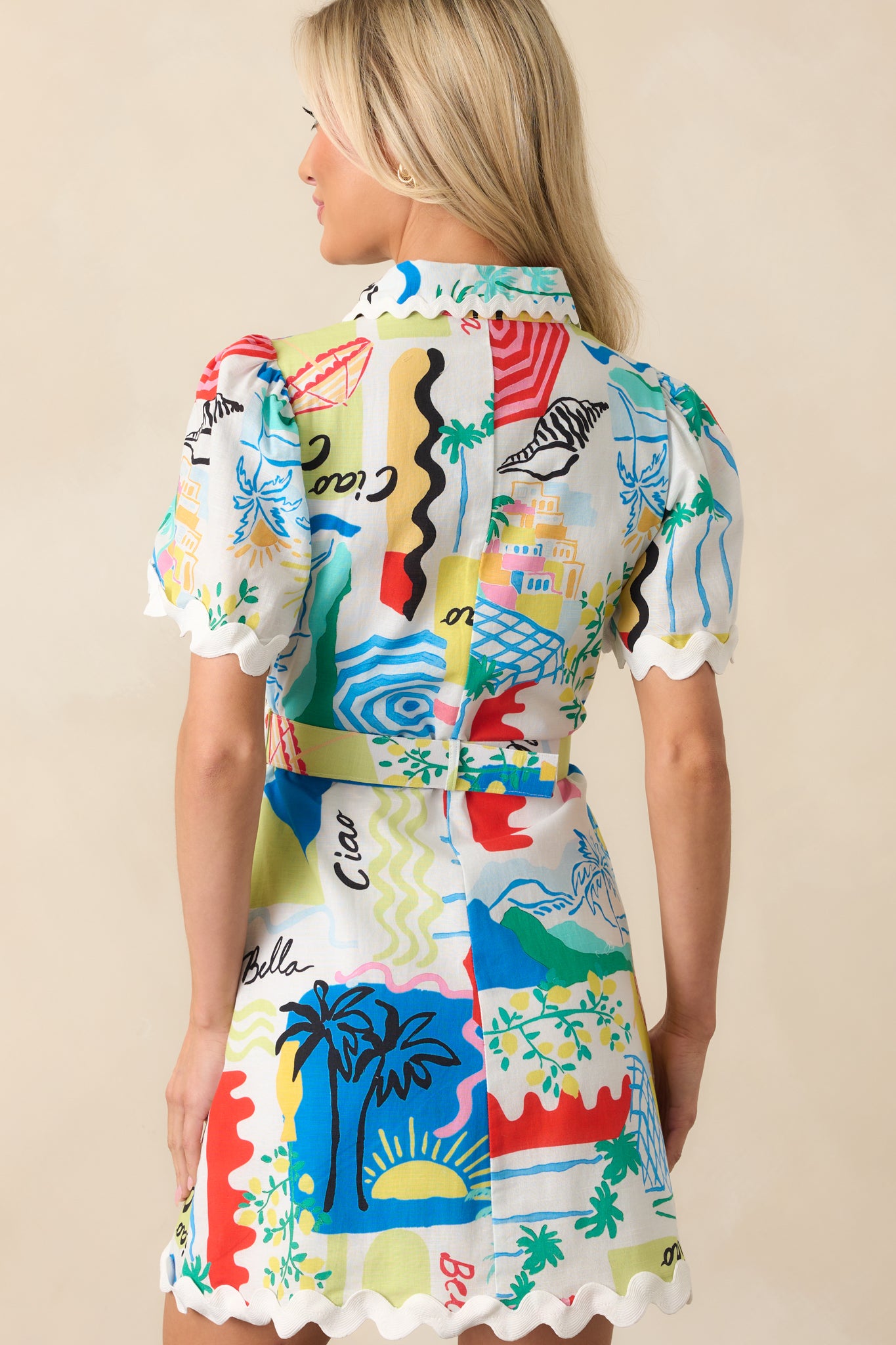 A back view of the dress showing the continuation of the tropical print, belt loops, and the gathered fit created by the belt from behind.