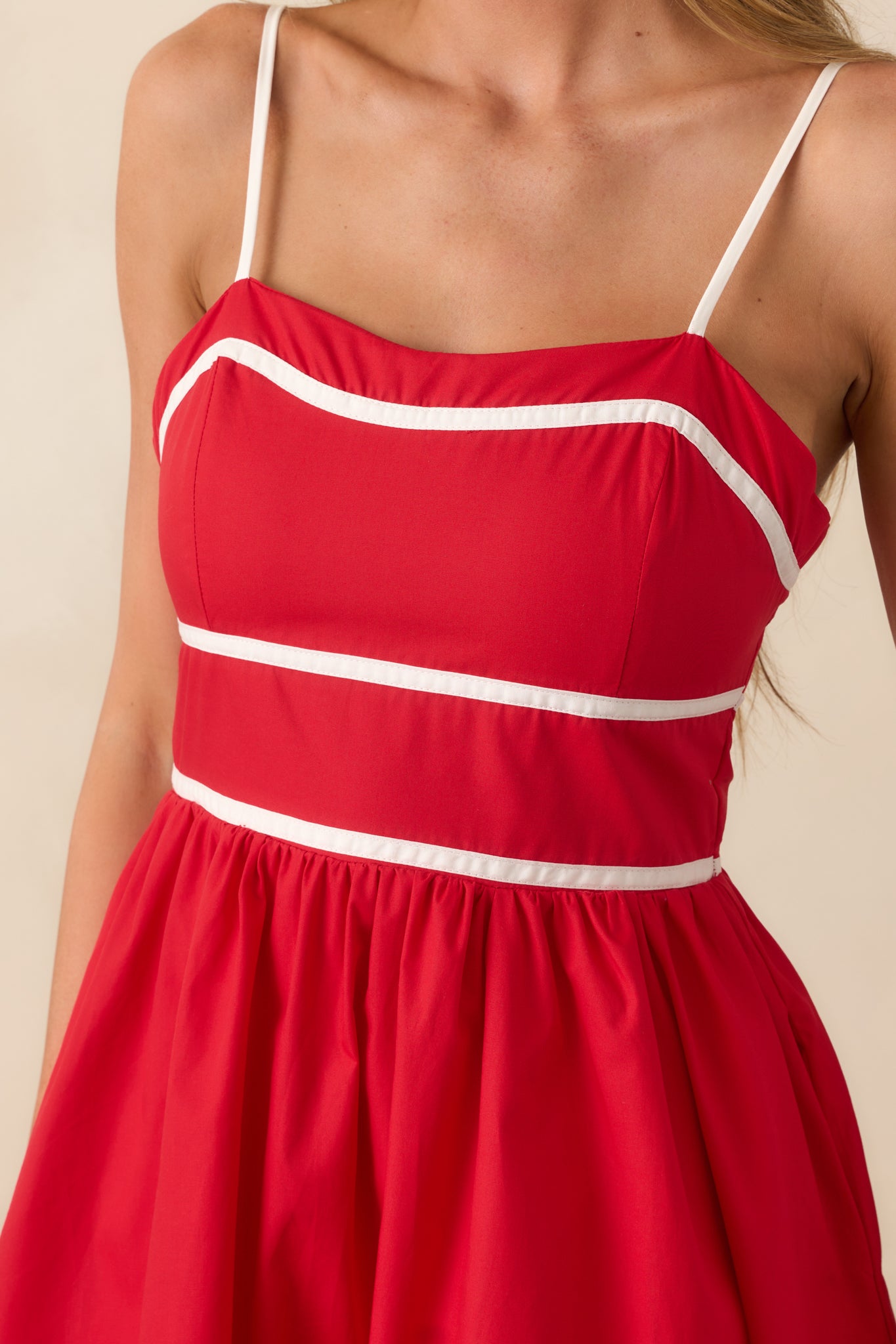 Focus on the waist area of the red mini dress, showcasing the self-tie back bow and seamless trim details.