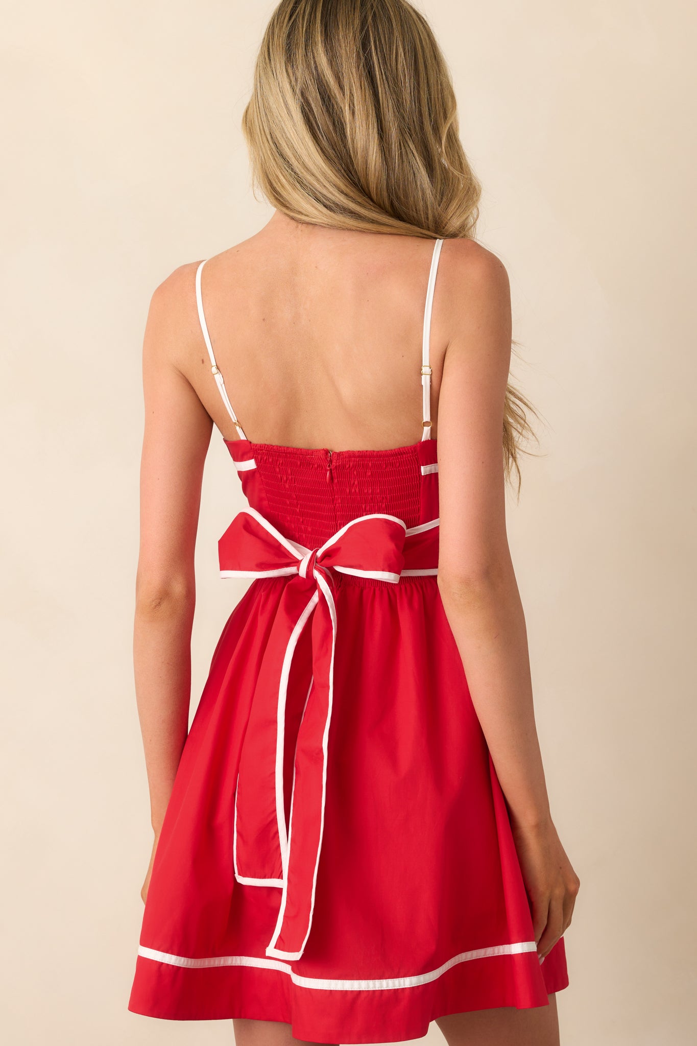 A view from behind, showing the self-tie bow, discrete zipper, and how the piping trim accents the dress.