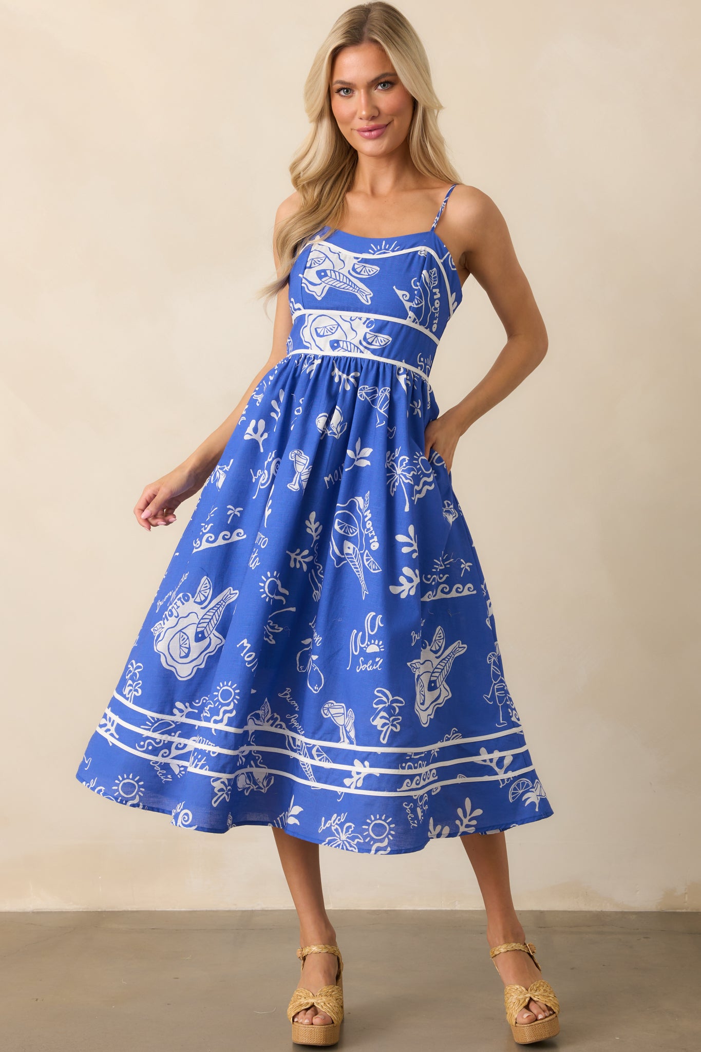 Blue midi dress with a squared neckline, adjustable straps, and a vibrant mojito print throughout.