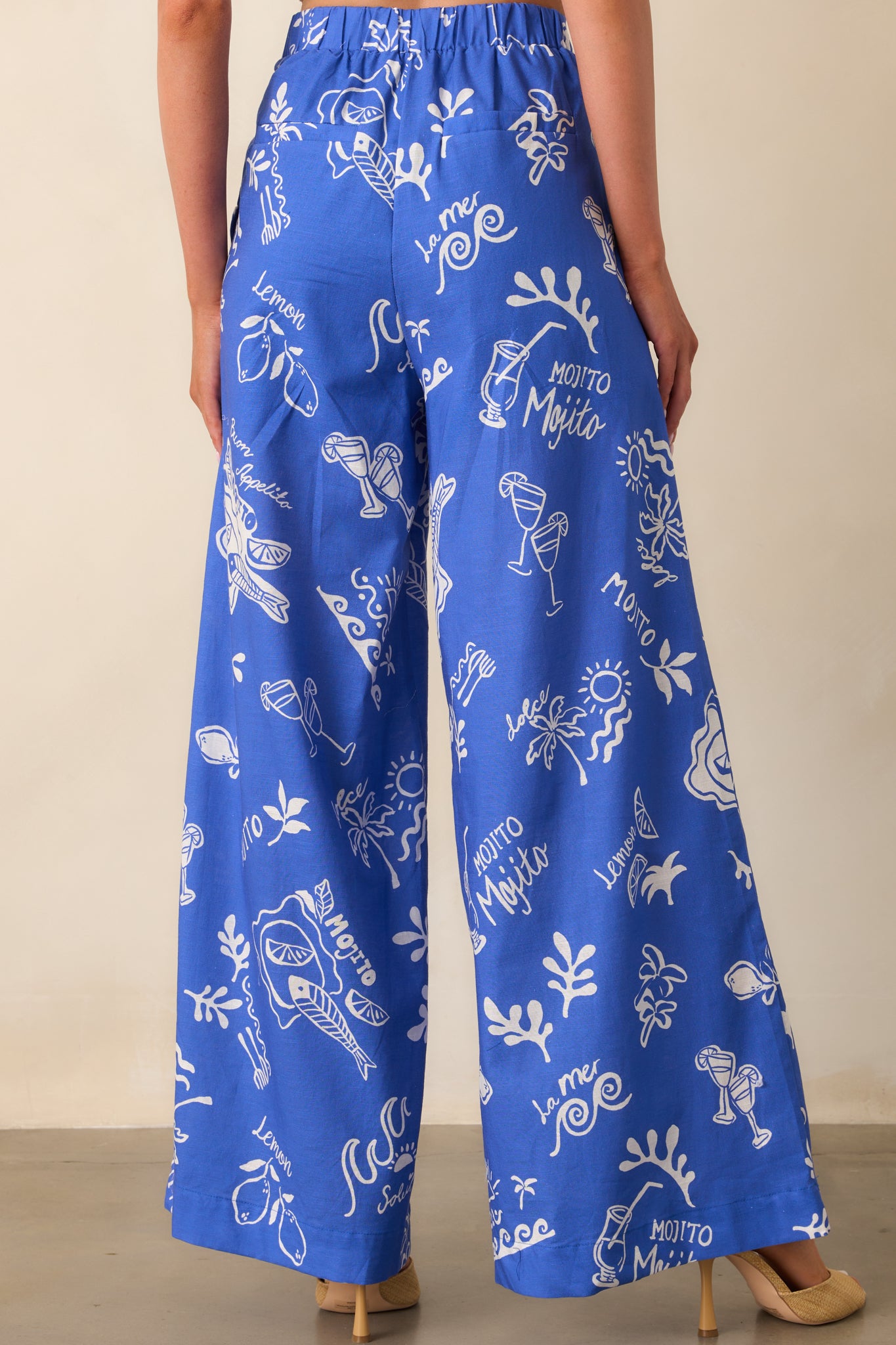 A back view of the blue pants featuring two faux back pockets and an elastic insert at the waistband for a comfortable fit.