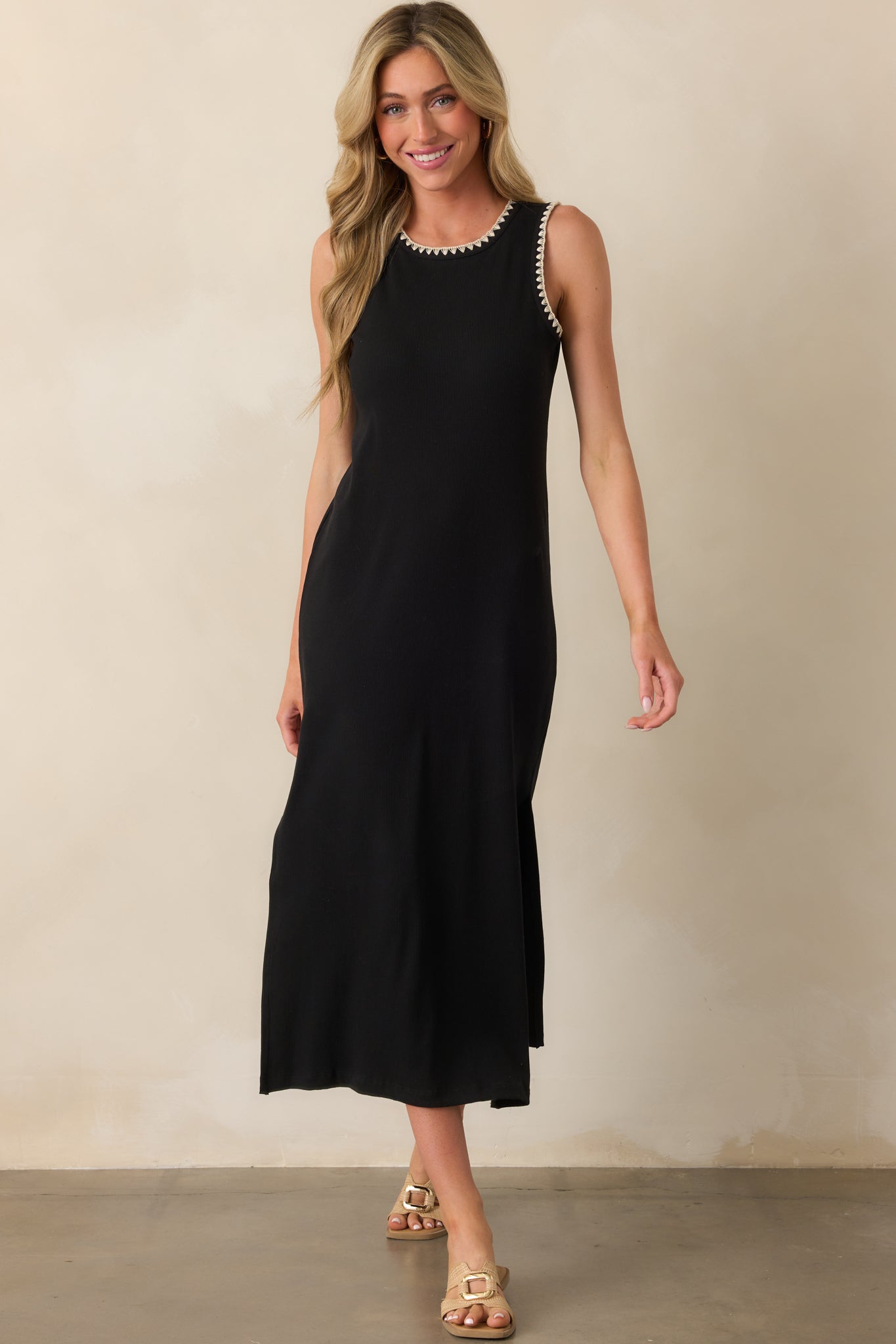 Black sleeveless midi dress crafted from ribbed fabric, designed with ivory stitching and side slits for added movement.
