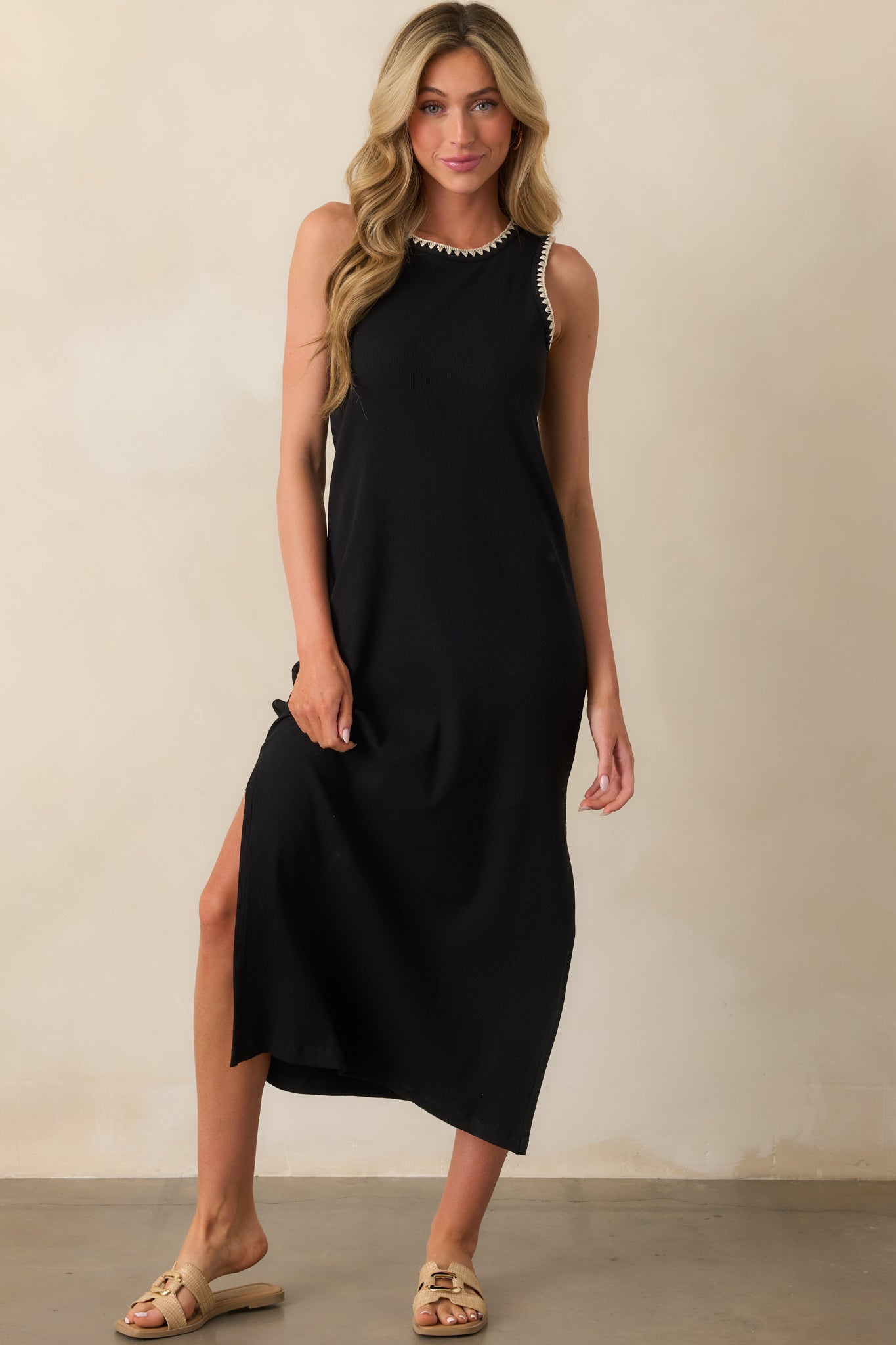 Minimalist black dress with light texture, contrast trim, and a relaxed midi shape that falls just below the knee.