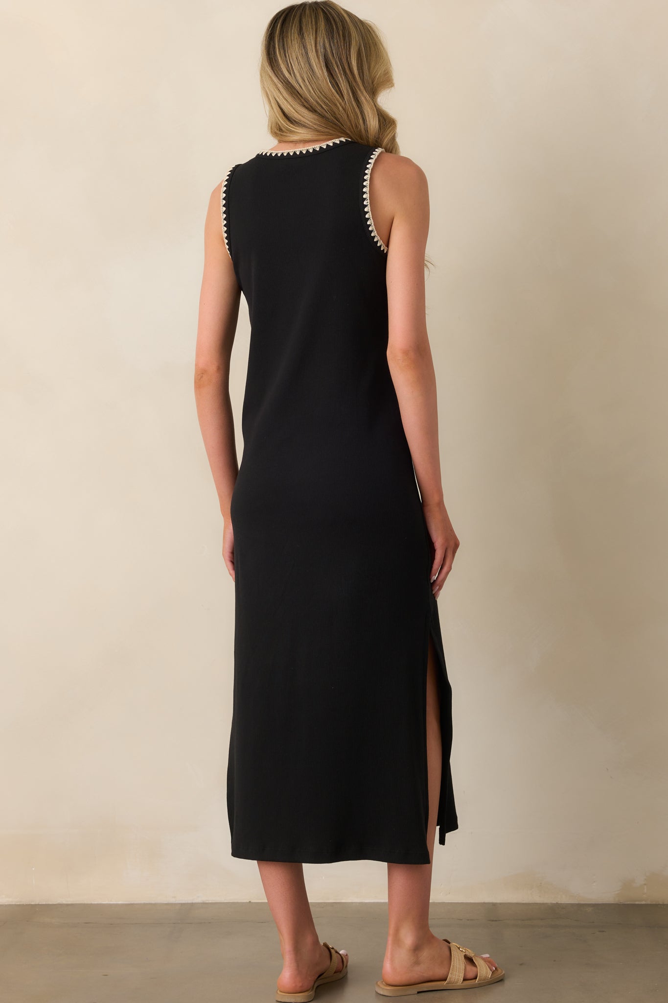 A view from behind showing the sleeveless cut, ribbed texture, and how the ivory trim outlines the back of the black midi dress.