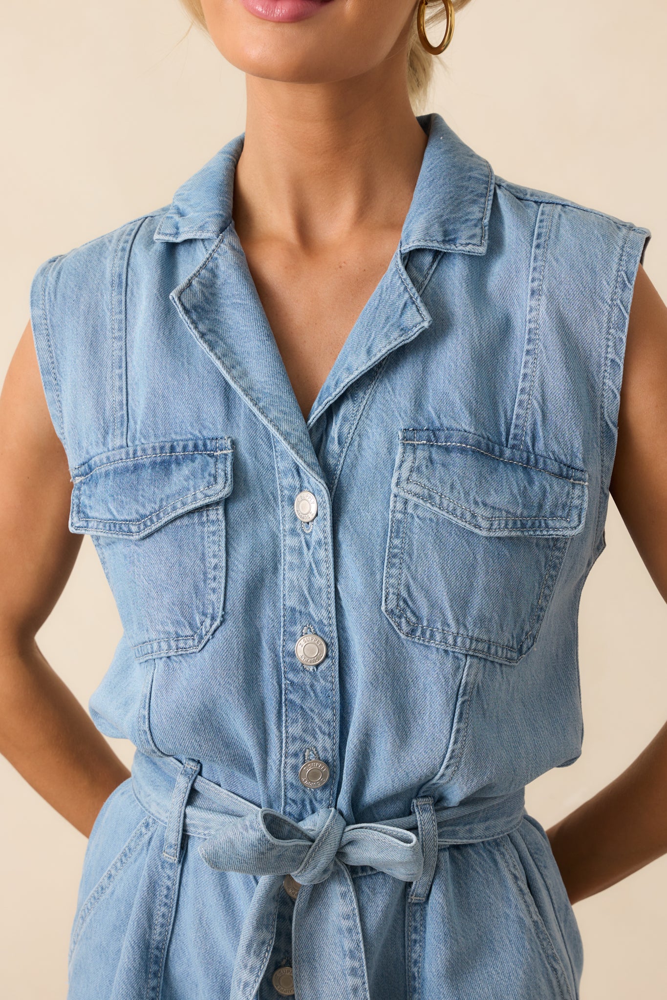 Close-up of the fabric and buttons, showing the light denim texture, stitching, and functional pocket flap.