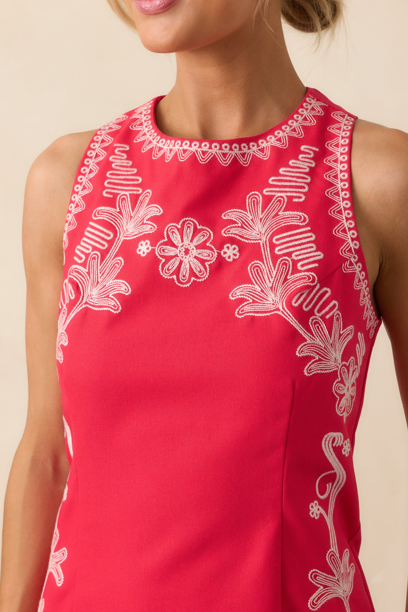 Close-up shot of the ivory floral embroidery on the red fabric showing the detailed stitching and texture.