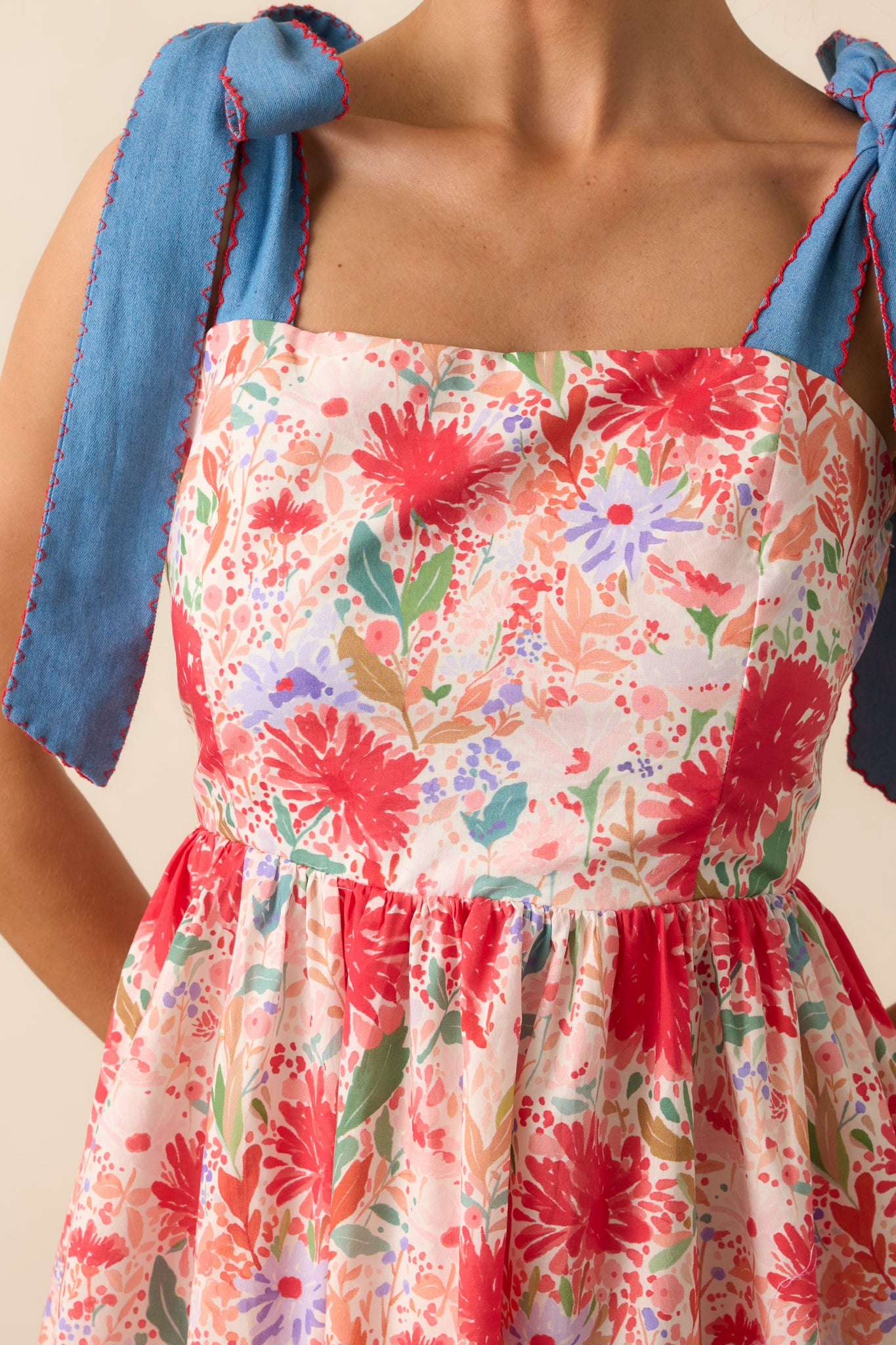 Close-up of the adjustable medium wash bow straps and floral print fabric texture.