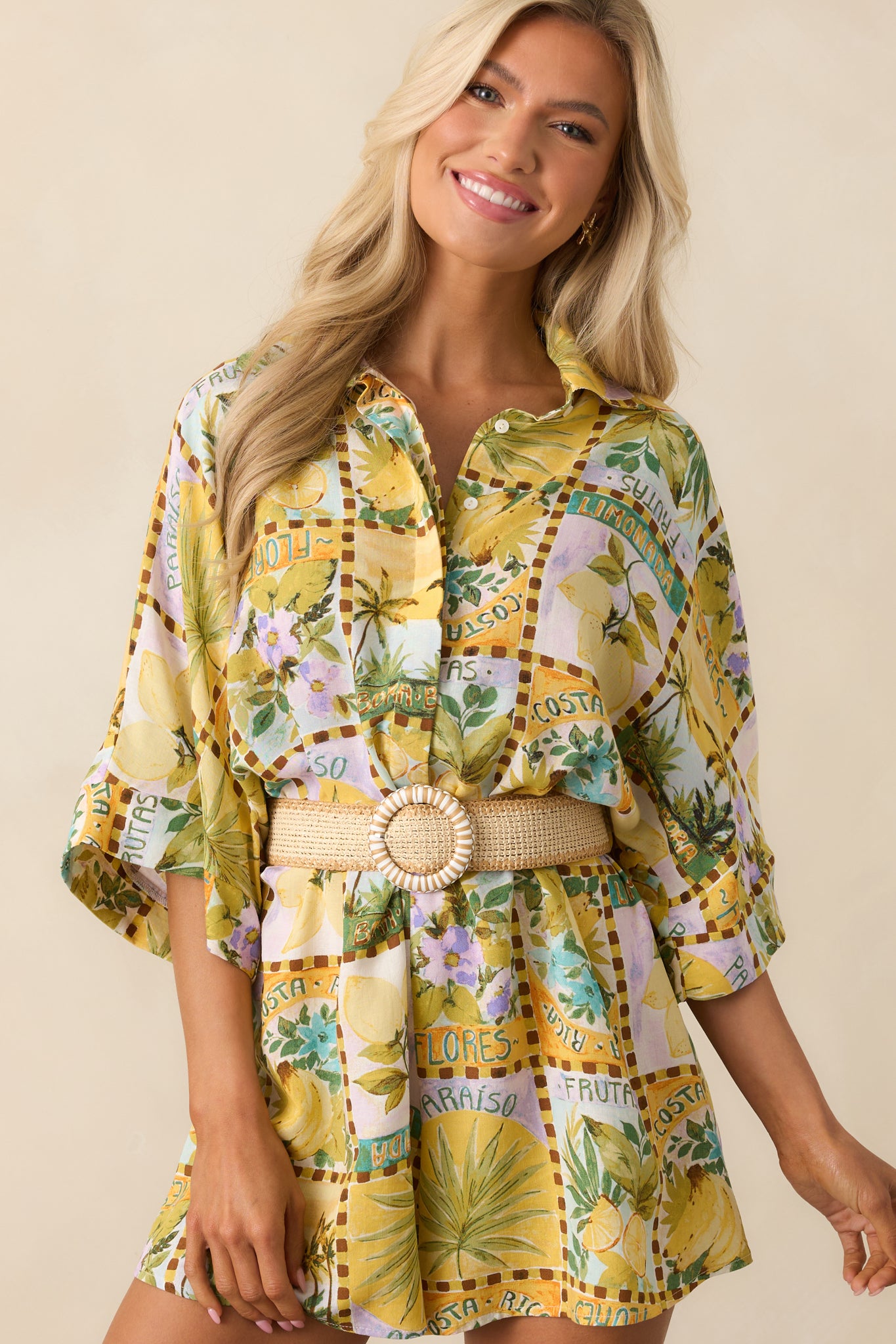 Upper-body close-up showing the collar, multicolor fruit print, and button detailing of the yellow romper.