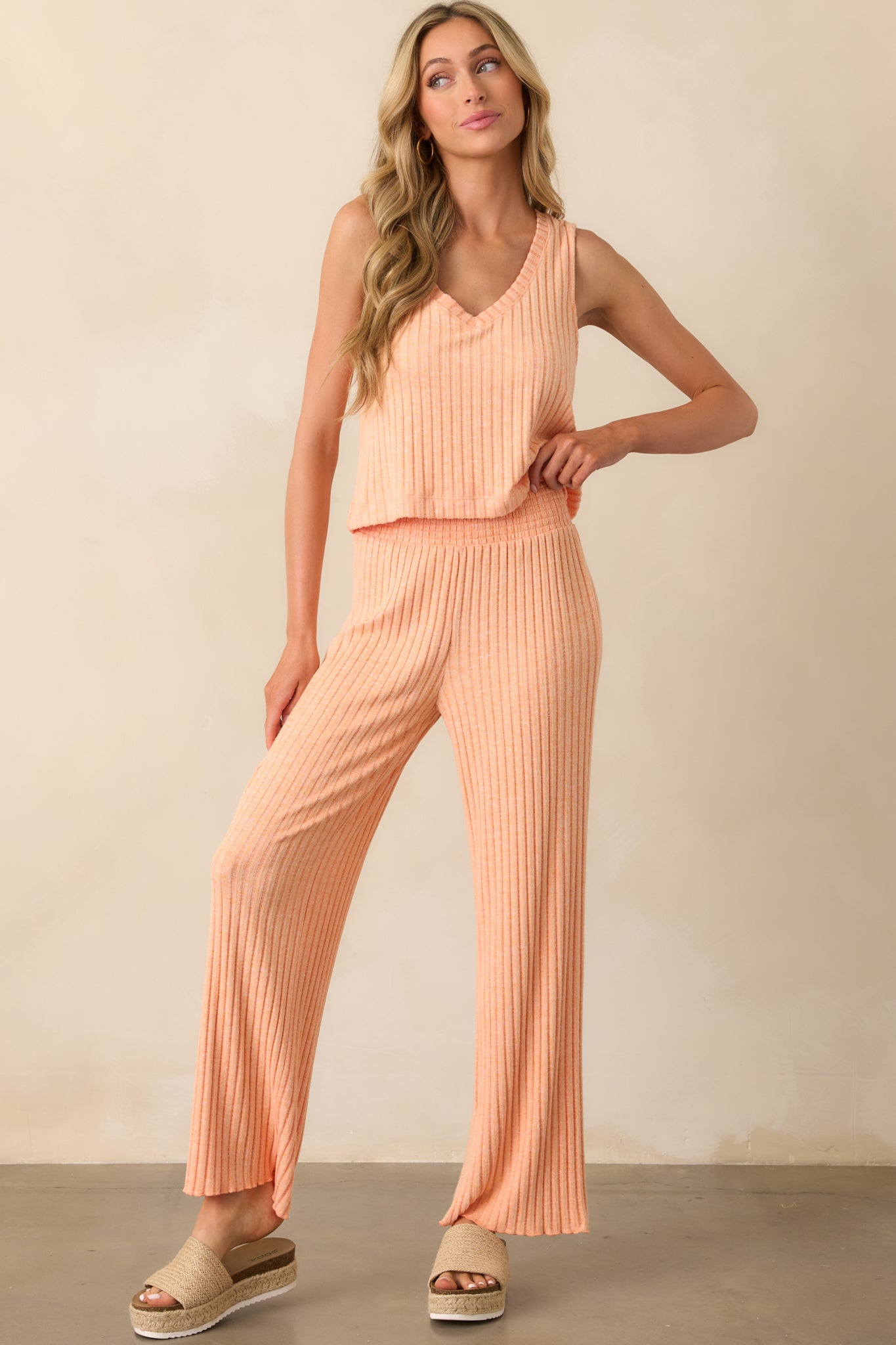 Full view of orange pants with a wide fully smocked elastic waistband and slightly flared wide legs.