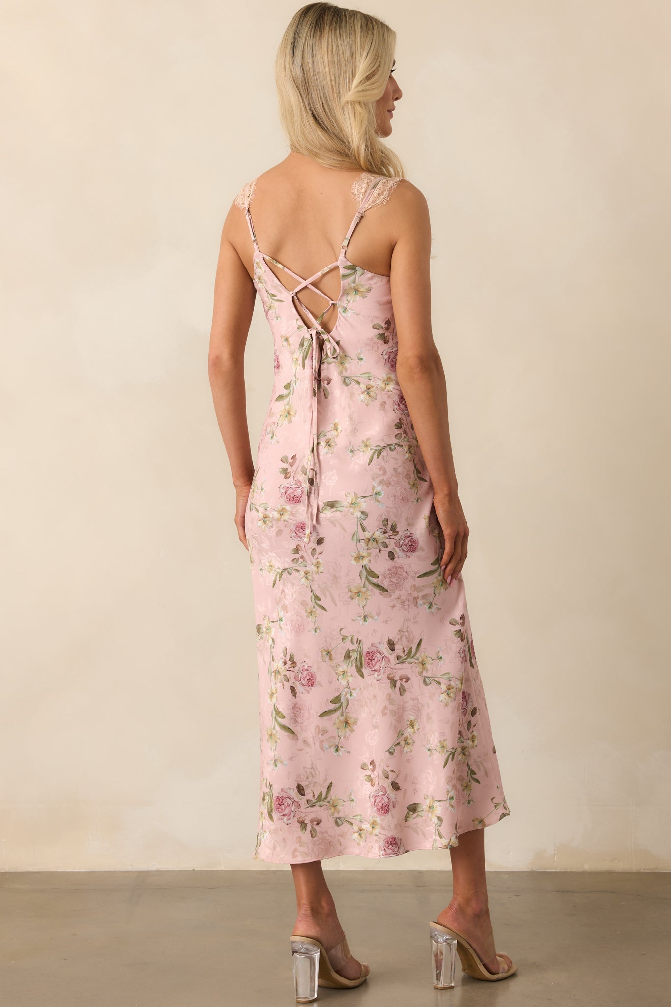 A view from behind of the rose pink dress, showing the open adjustable lace-up back and continuation of the floral print.