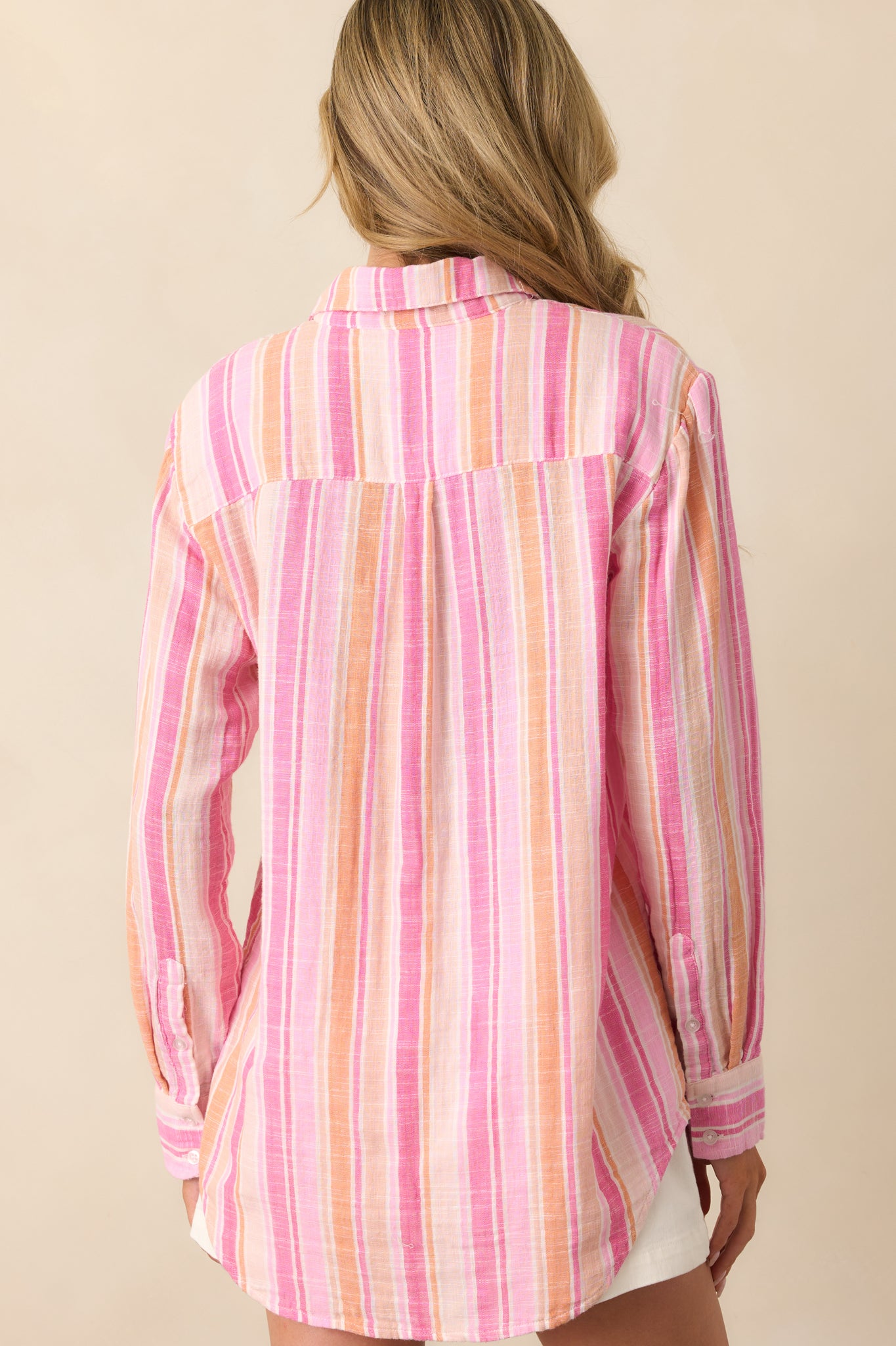 A view from behind of the pink striped top, showing the collar, long sleeves, and overall relaxed fit.
