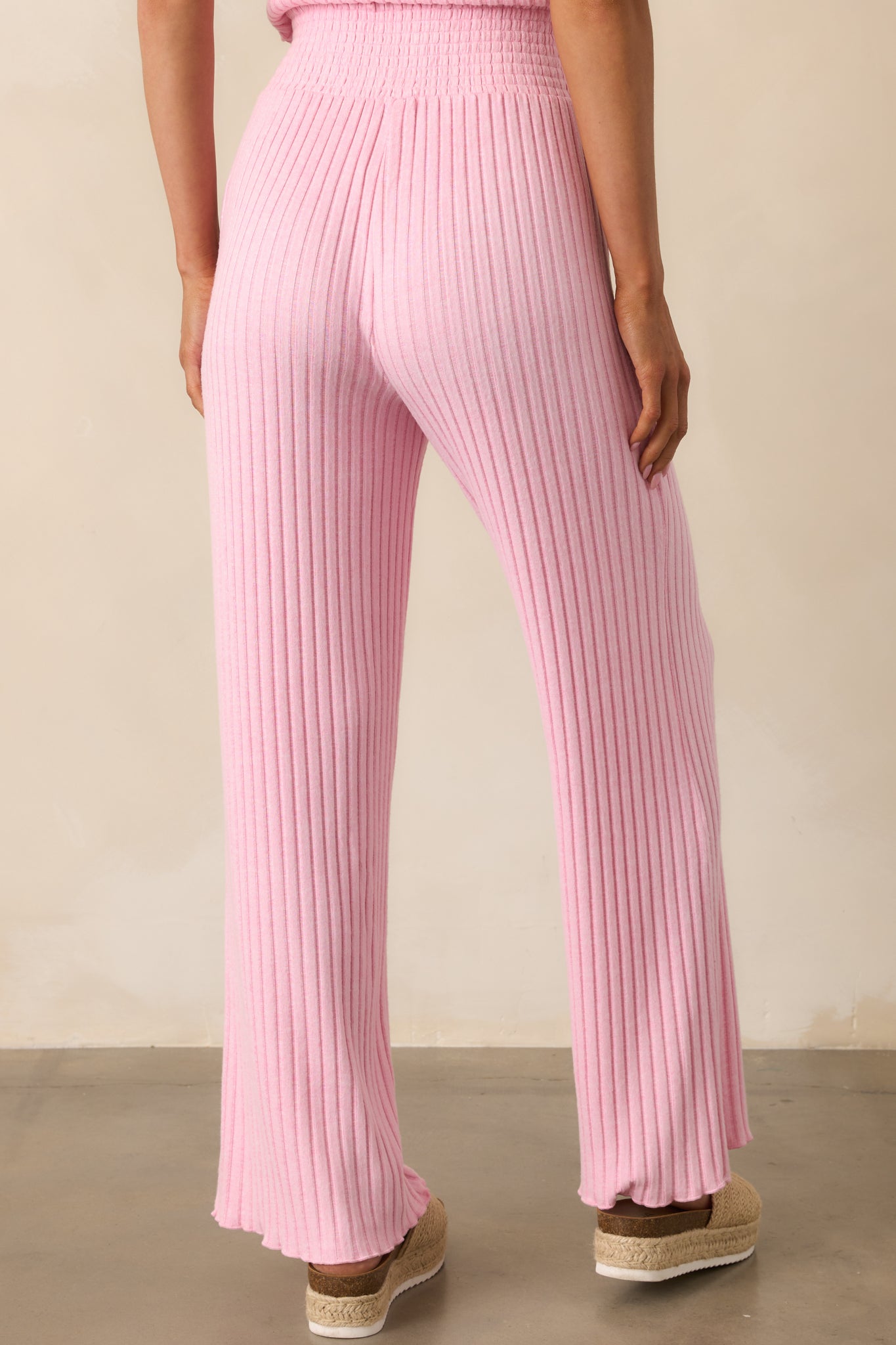 A view from behind of the pink pants, showing the wide smocked waistband and flare of the legs.